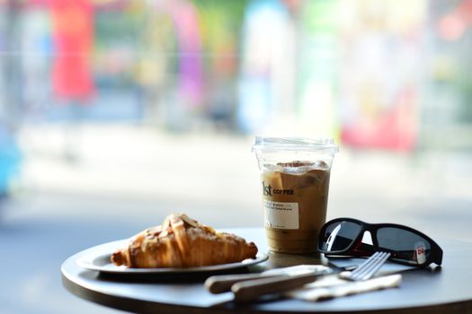 Stylish coffee break scene with iced latte and croissant on a sunny day.
