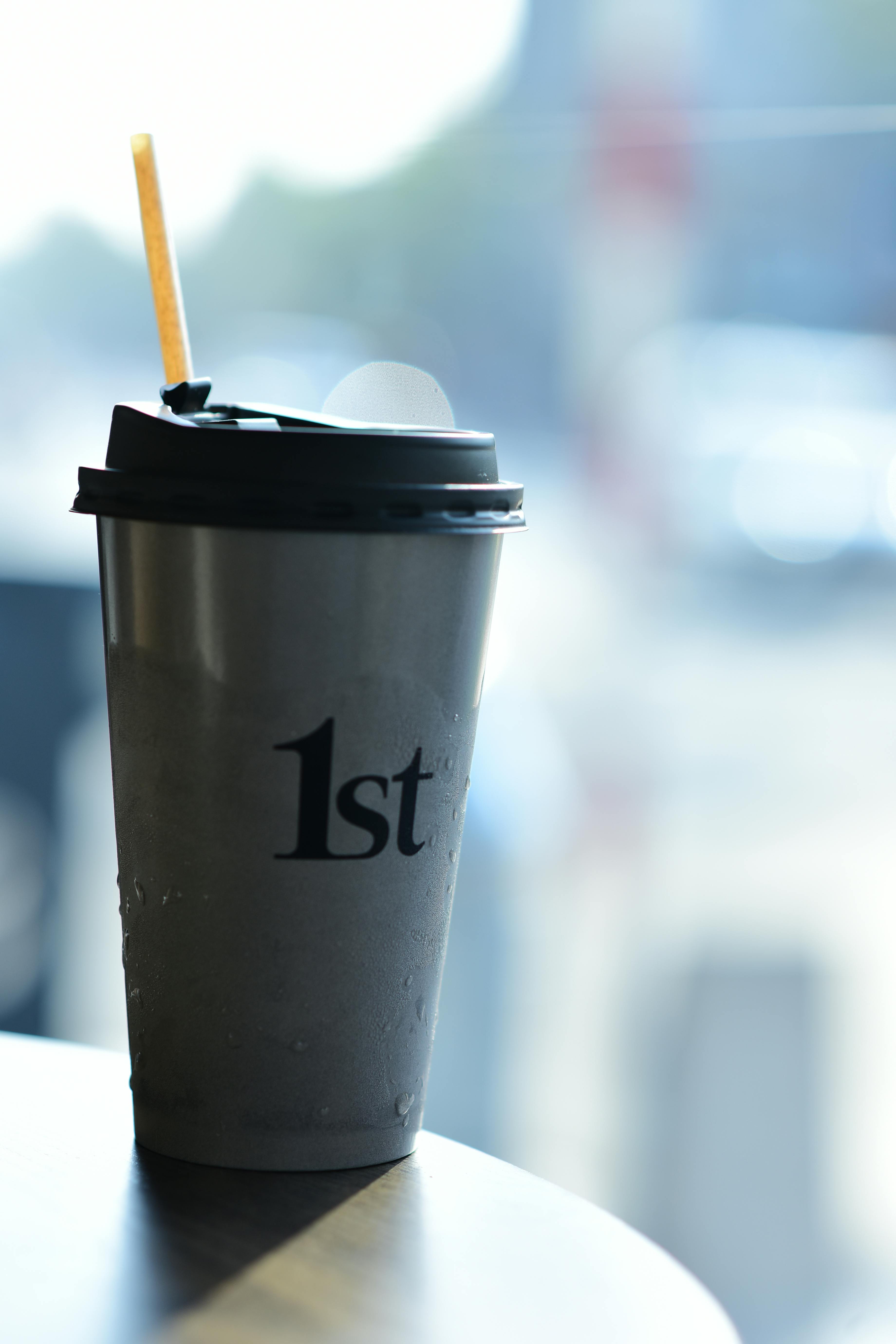 Δωρεάν Ένα κομψό φλιτζάνι καφέ με καλαμάκι και κείμενο «1st», ιδανικό για μια μοντέρνα ατμόσφαιρα καφέ. Φωτογραφία από στοκ φωτογραφιών