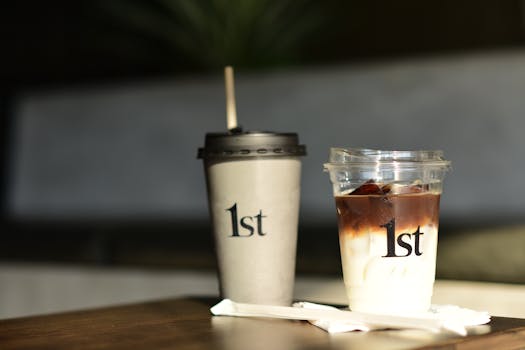 A close-up of branded coffee cups on a wooden table with sunlight.