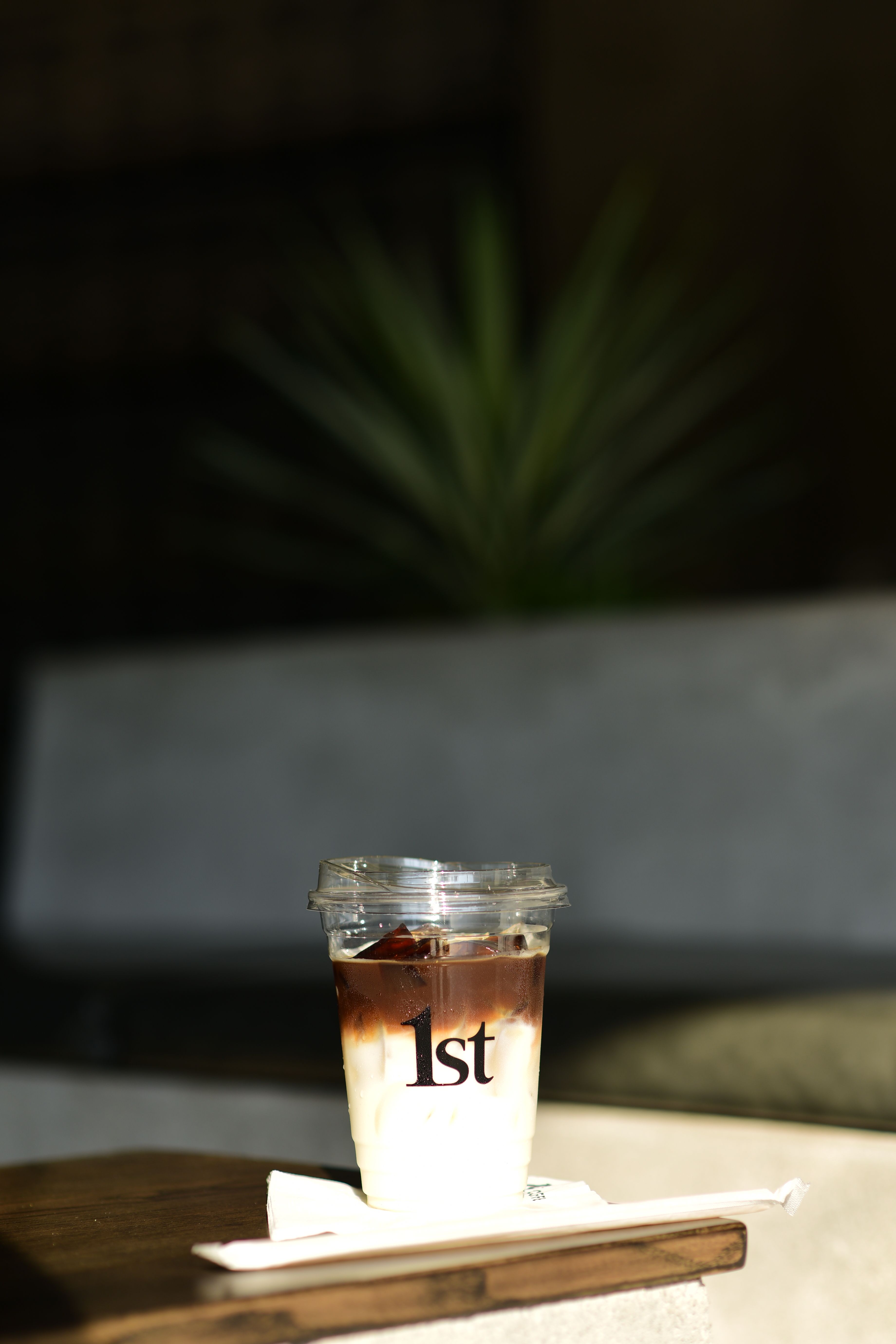 Artistic shot of iced coffee in a sunlit cafe setting, highlighting shadows and texture.