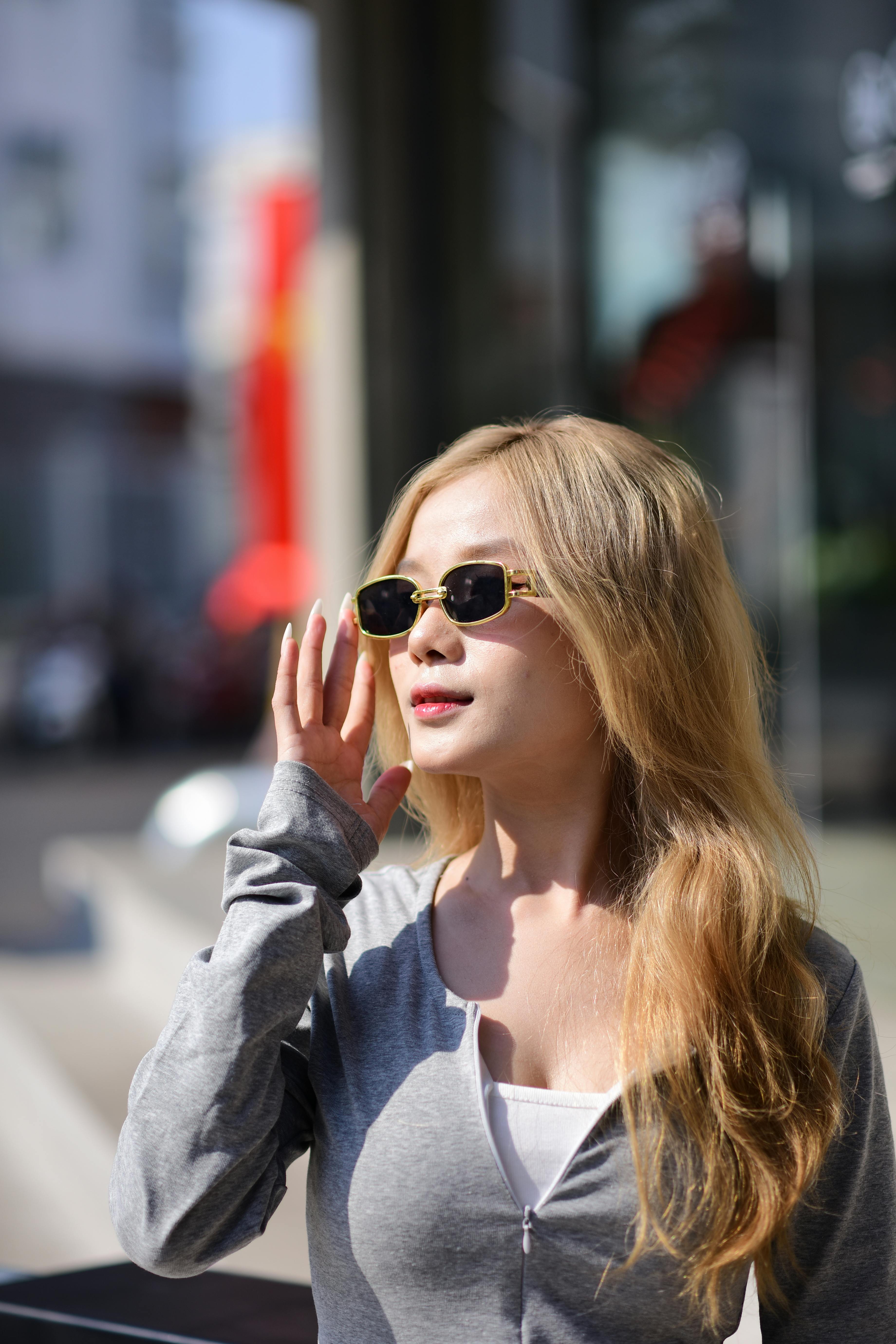 Free Stylish woman wearing sunglasses outdoors in a urban setting during a sunny day. Stock Photo