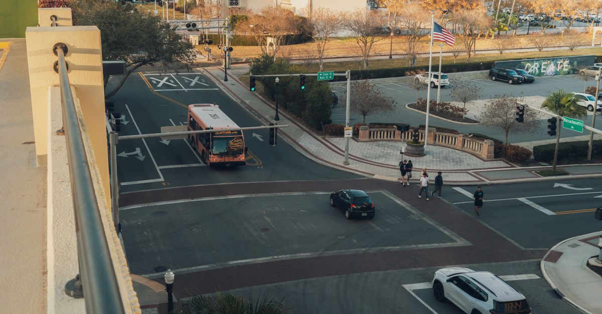 Aerial view of a busy street intersection in downtown with a bus and pedestrians crossing.