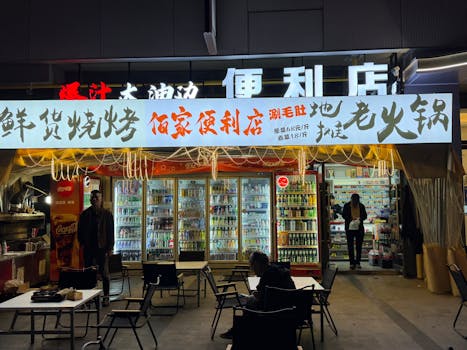 Illuminated convenience store at night with people shopping and eating outside.