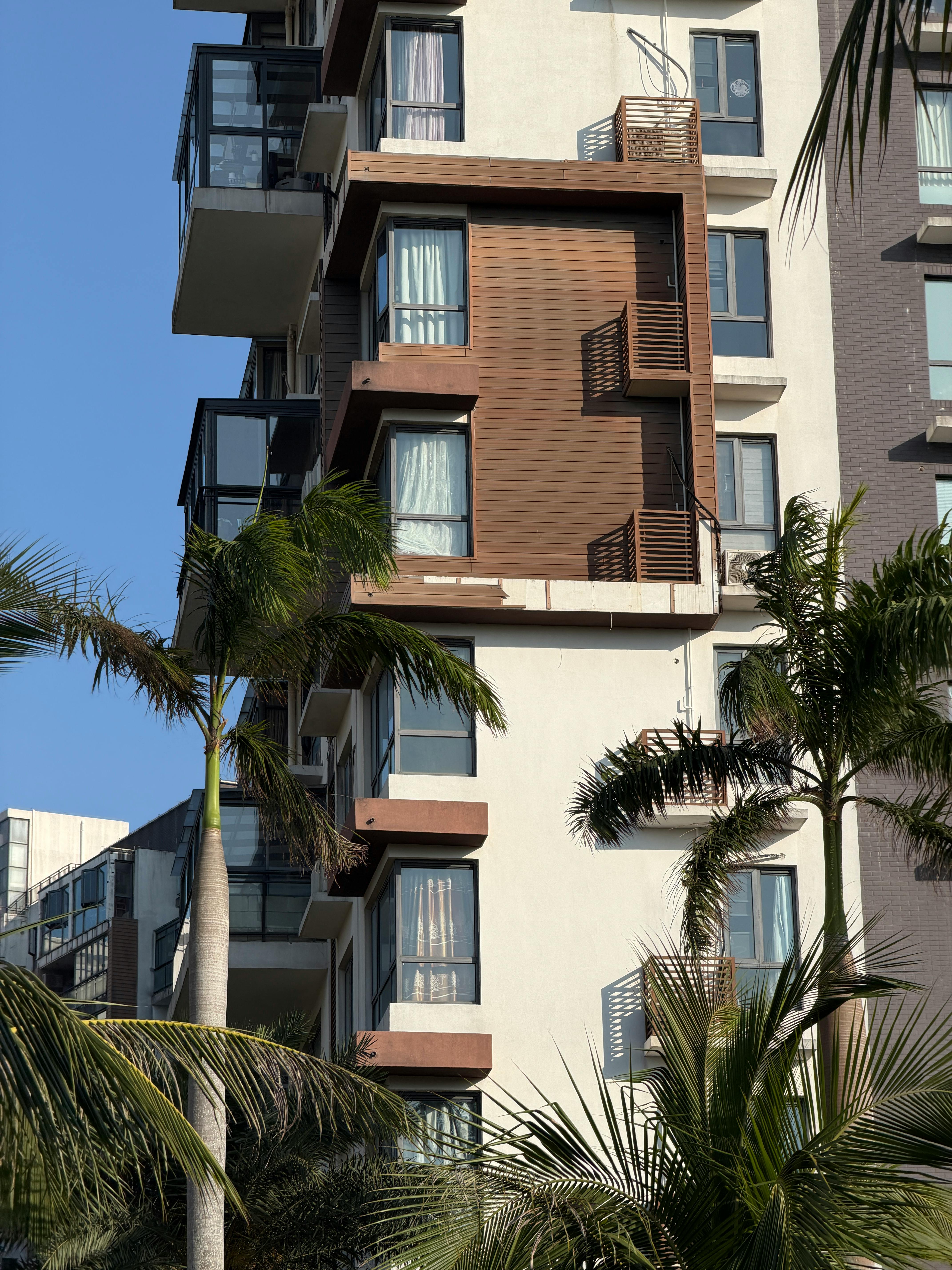 Kostenlos Modernes Apartmentgebäude unter strahlend blauem Himmel und Palmen. Stock-Foto