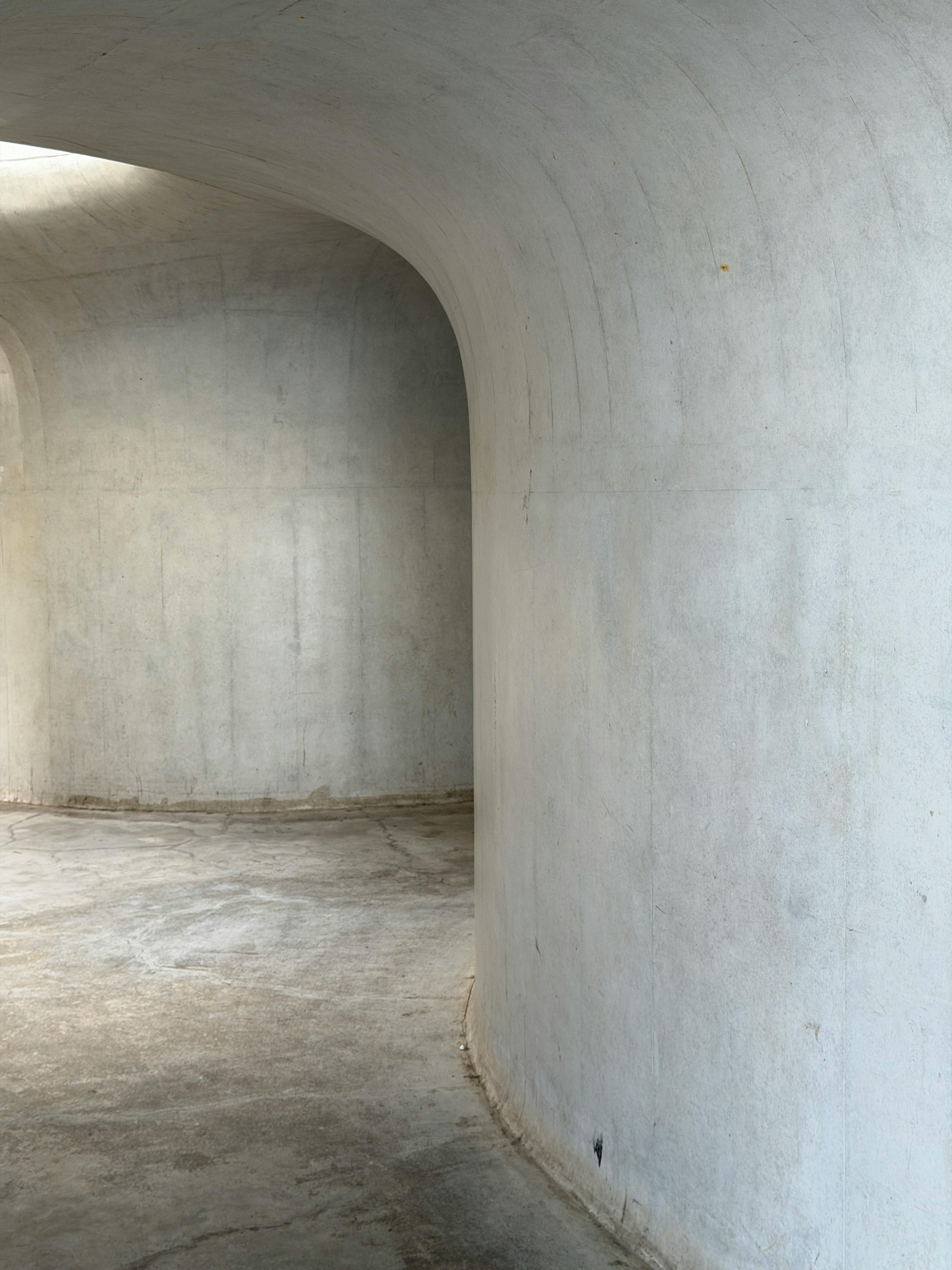 Free Curved concrete walls capture minimalist architecture. Ideal for modern design concepts. Stock Photo