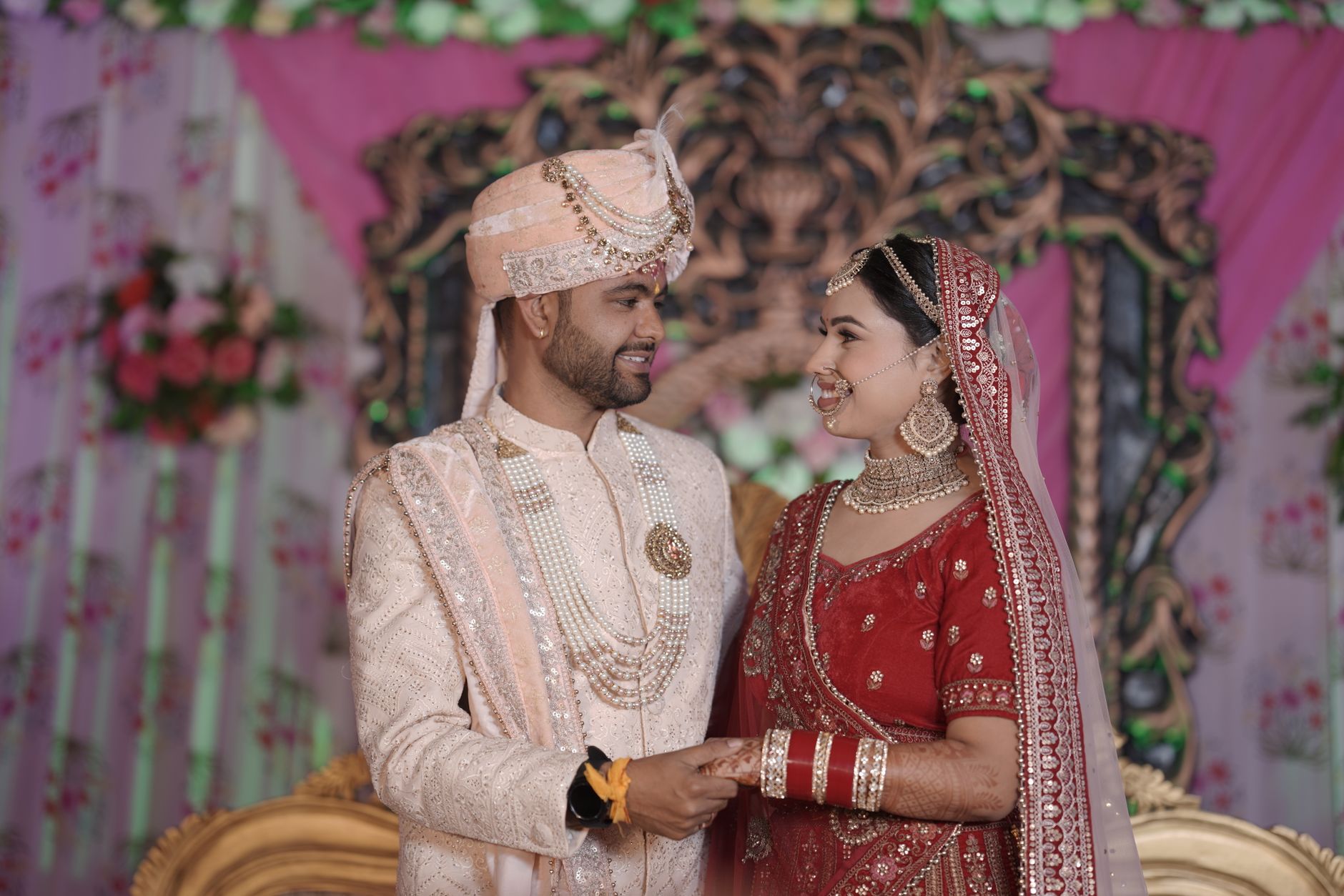 A happy Indian couple in traditional attire celebrating their wedding ceremony indoors.