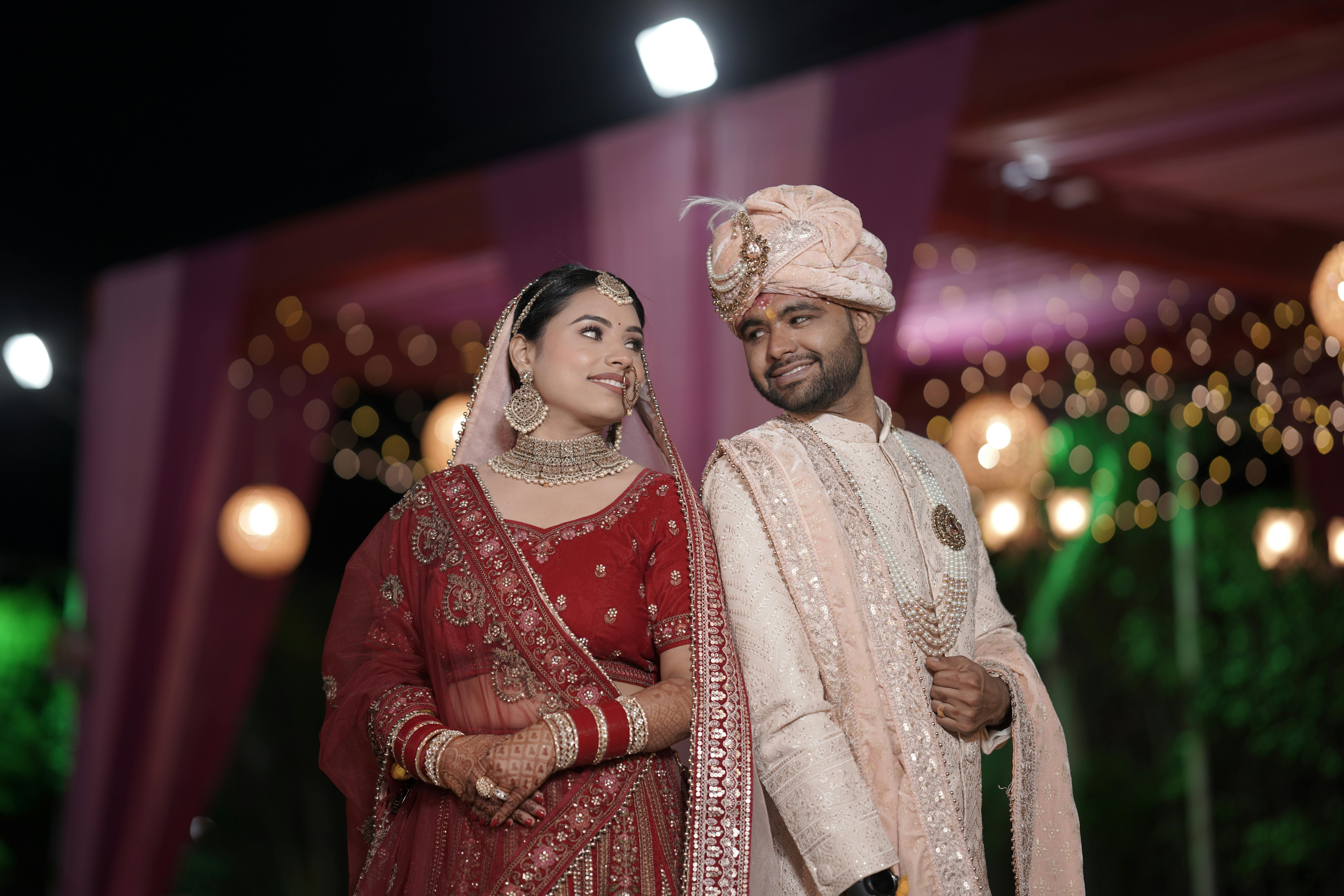 Traditional Indian wedding couple posing elegantly in vibrant attire during nighttime celebration.
