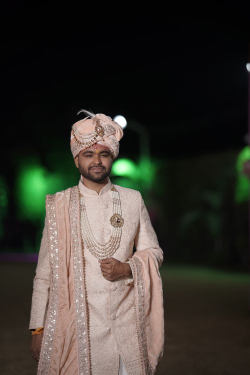 Free Indian groom wearing a traditional sherwani and turban at night. Stock Photo