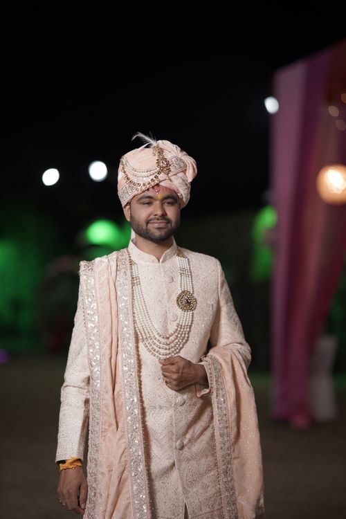Free Elegant Indian groom posing in ornate sherwani and turban, nighttime outdoor wedding. Stock Photo