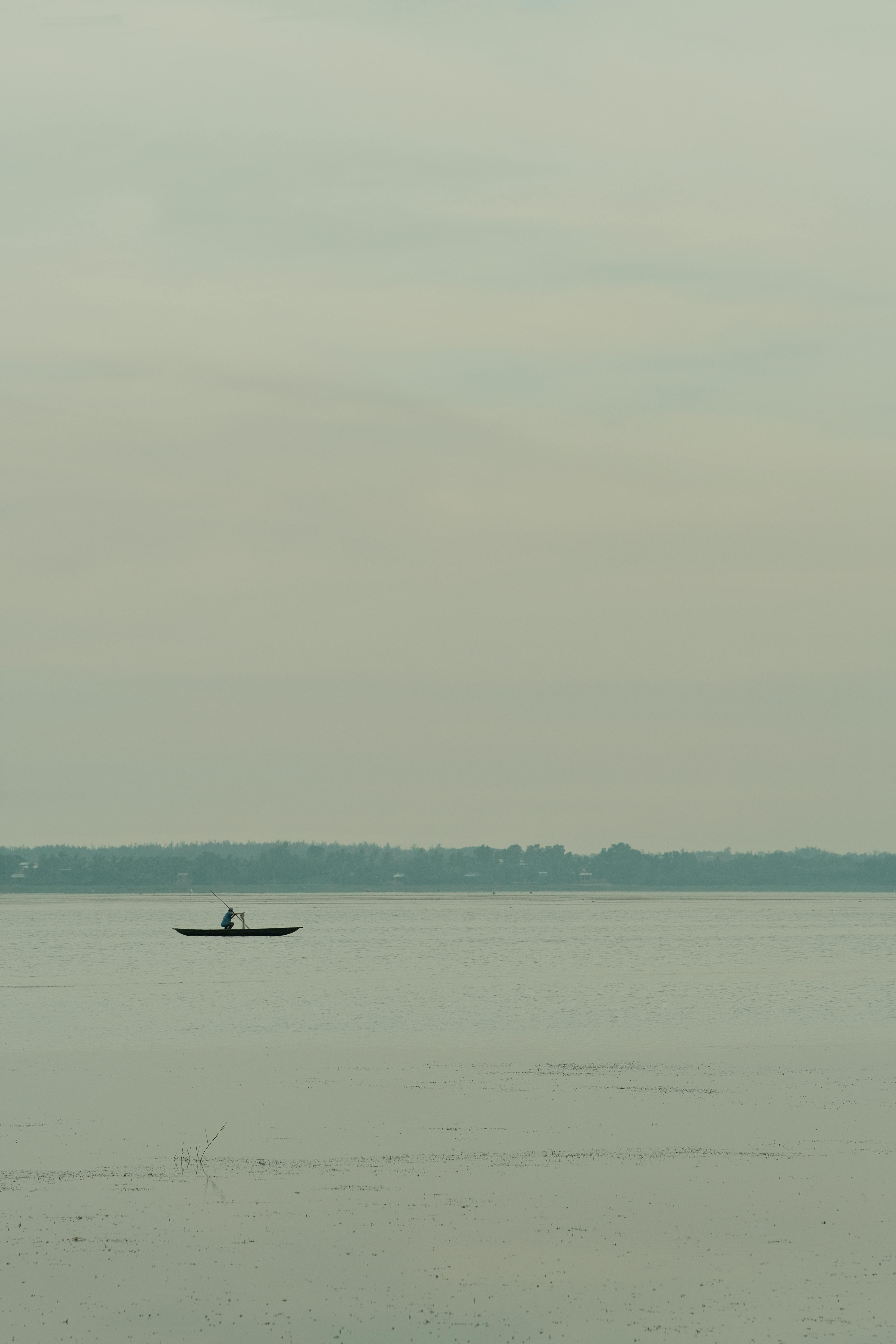 Kostenlos Eine friedliche Szene: Ein einsamer Fischer in einem Boot auf einem stillen See in Vietnam. Stock-Foto