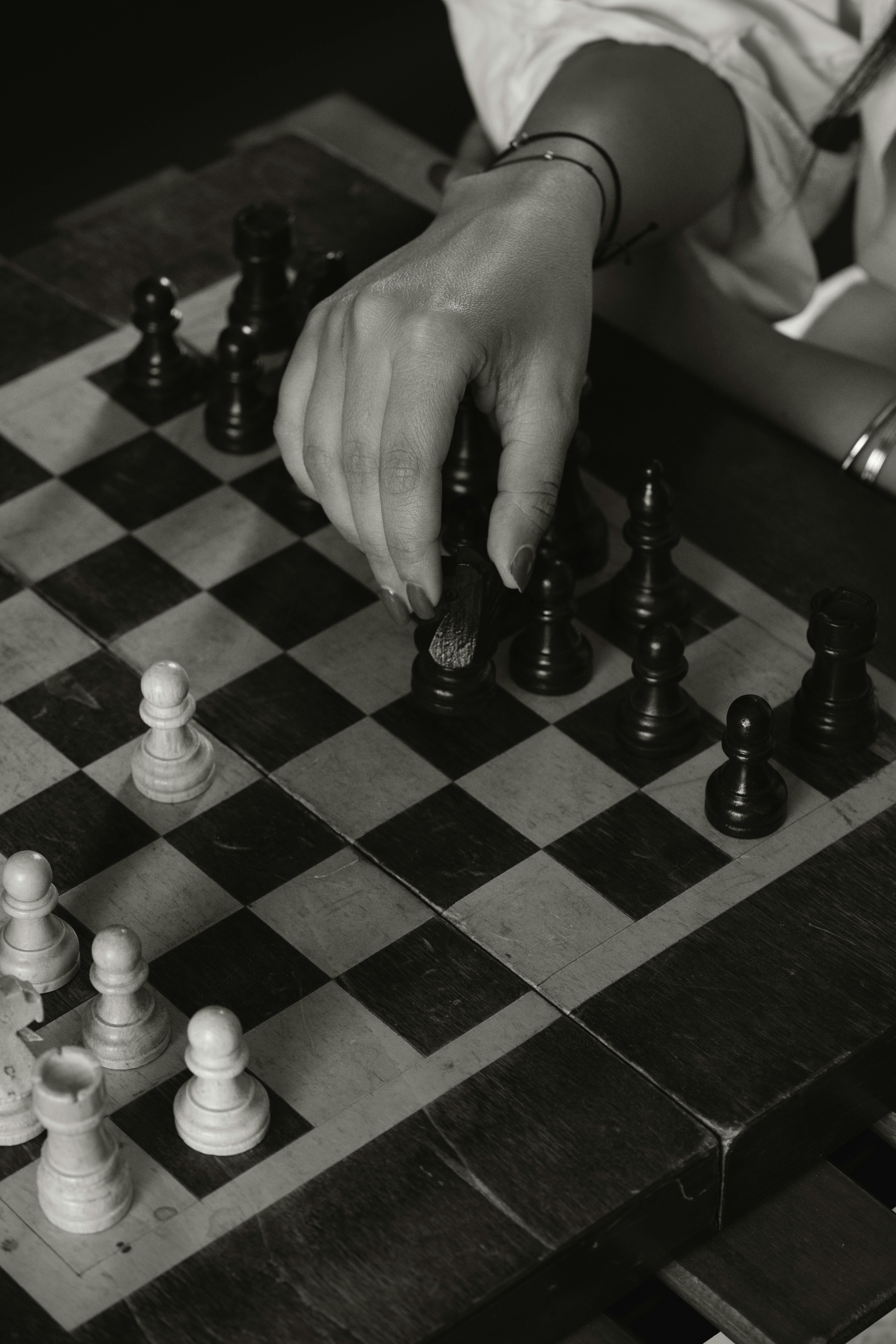 Gratis Primo piano di una mano che muove un pezzo degli scacchi su una scacchiera, sottolineando la strategia. Foto a disposizione