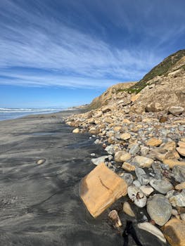Rocky shoreline along Torrey Pines State Beach under clear blue sky, San Diego, California.