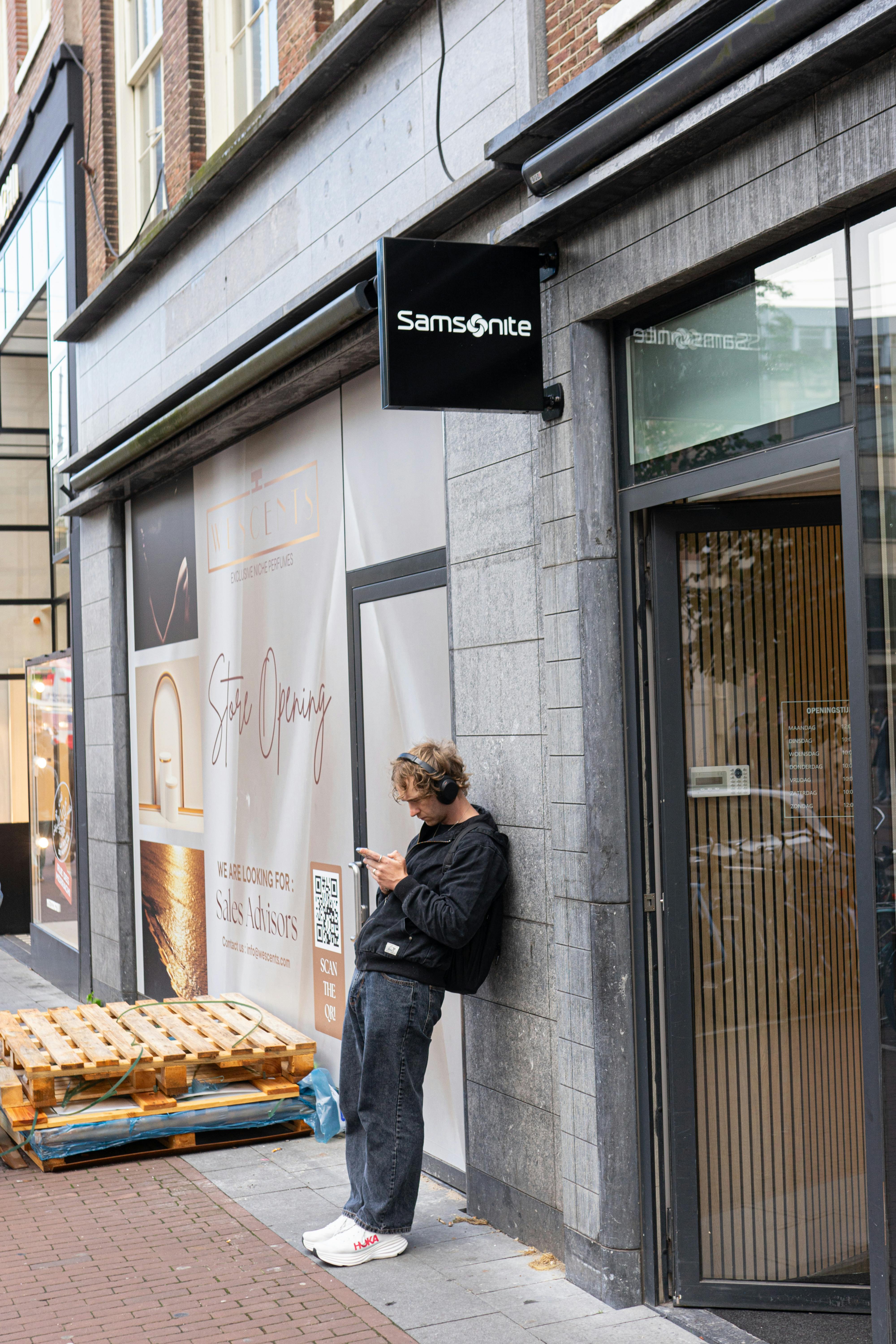 無料 アムステルダムの店先で携帯電話をチェックする若者の何気ない光景。 写真素材