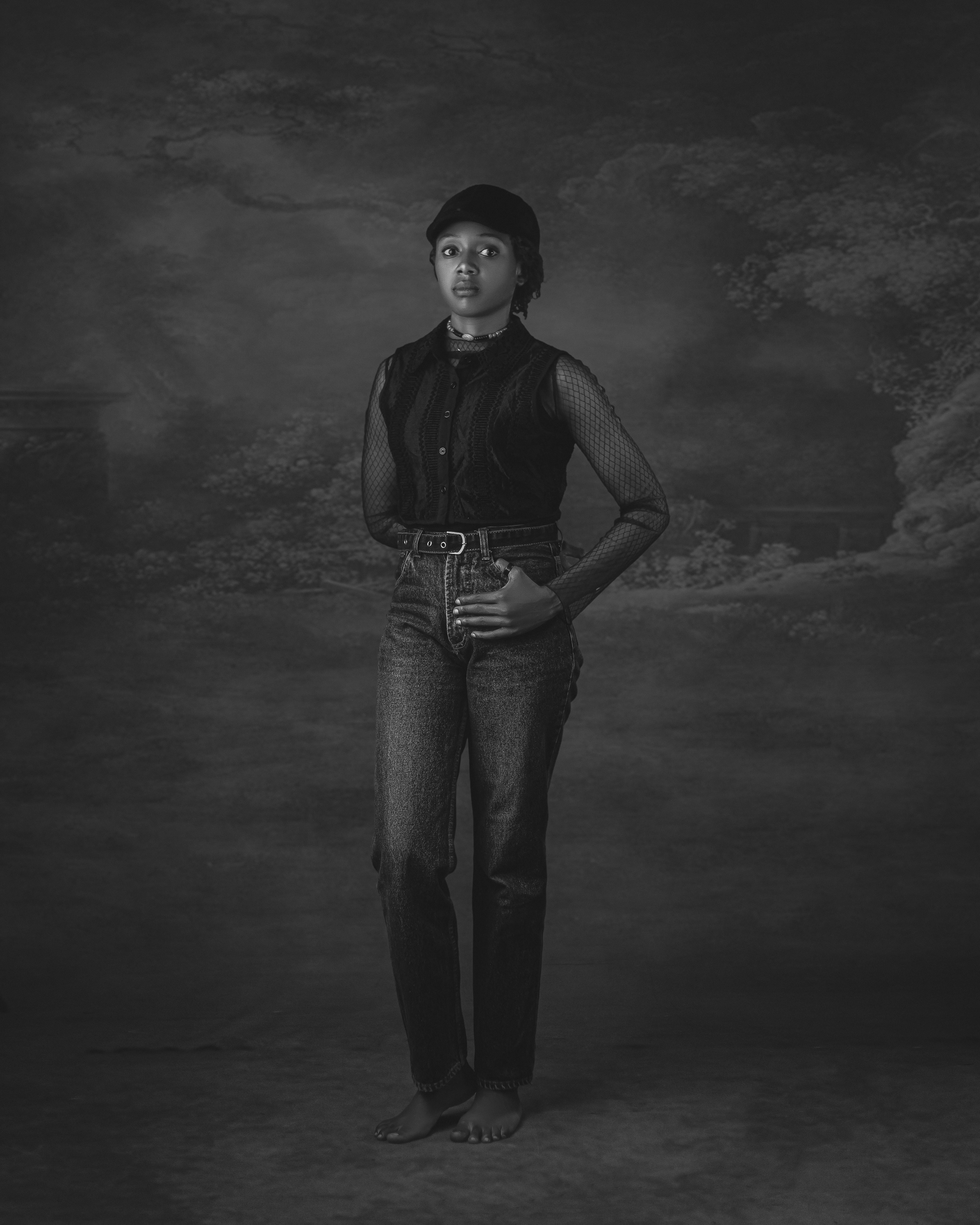 Kostenlos Schwarz-Weiß-Porträt einer jungen Frau in Jeans und ärmellosem Top in einem künstlerischen Umfeld. Stock-Foto