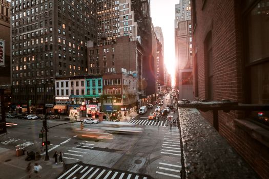 Capture of busy New York City street with iconic buildings during sunset.