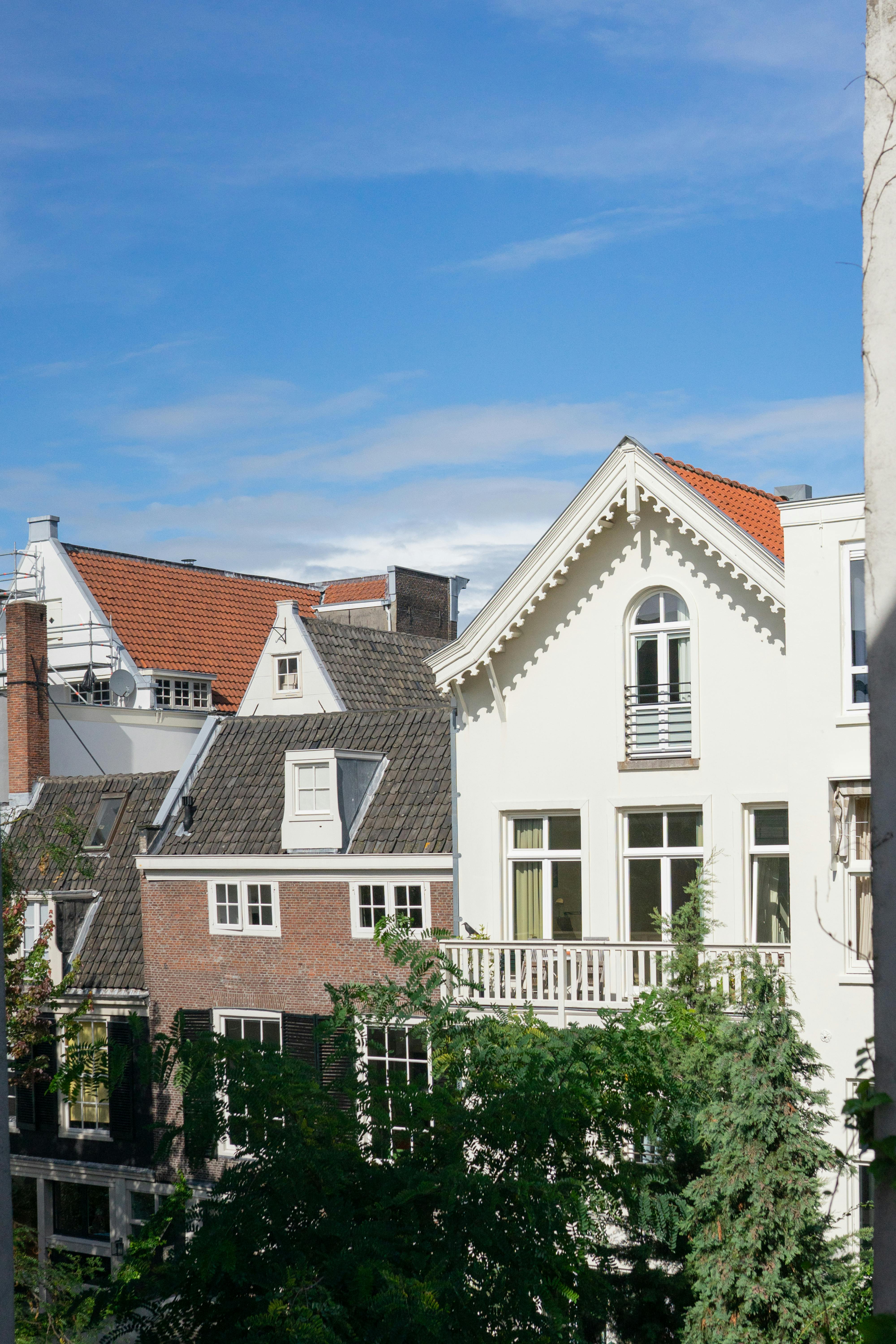 бесплатная Живописный вид на традиционные амстердамские дома с двускатными крышами в солнечный день. Стоковое фото