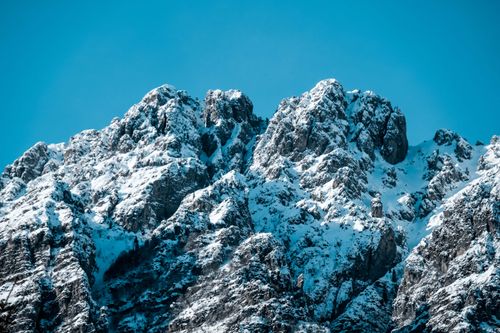 Free Snow-covered mountain peaks under a clear blue winter sky. Majestic and serene landscape. Stock Photo