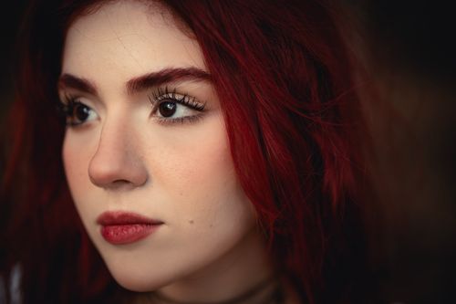 Free A detailed close-up portrait of a woman with striking red hair and expressive features. Stock Photo