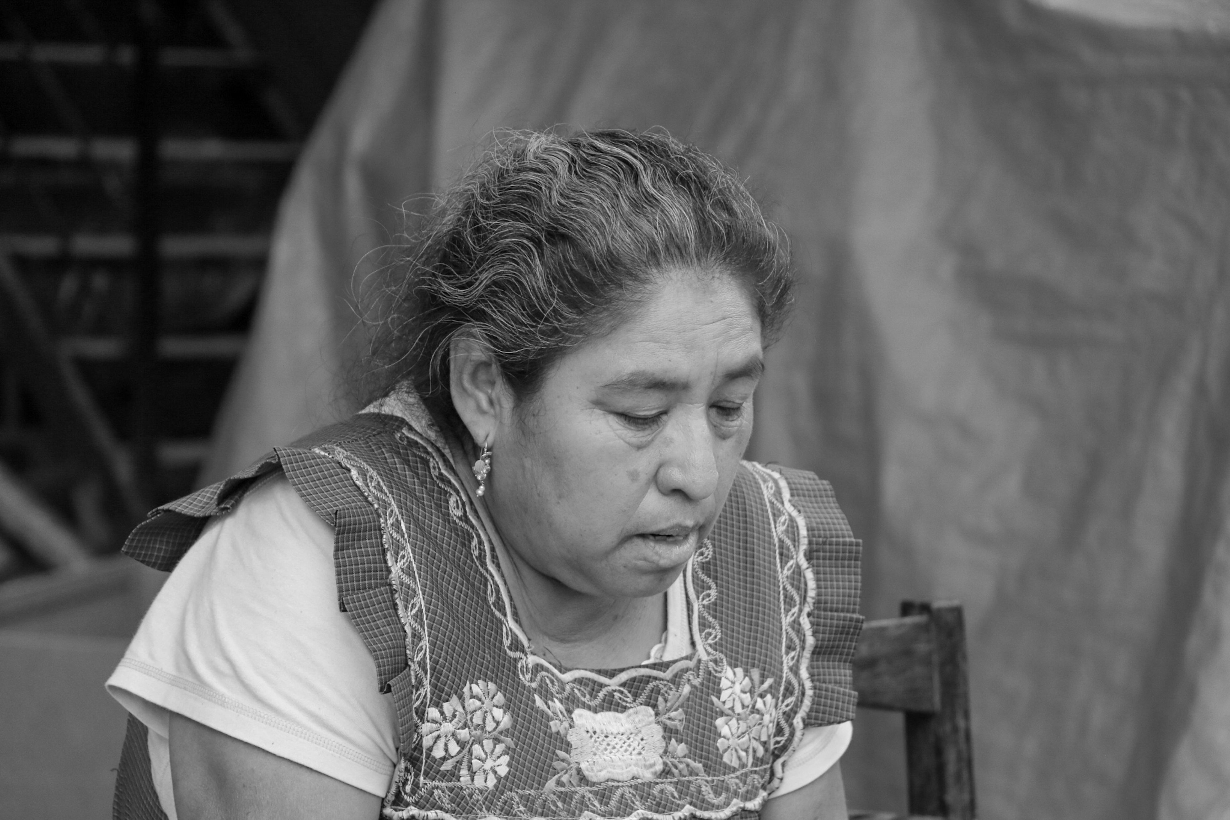 A contemplative woman in traditional clothing captured in a candid black and white shot.