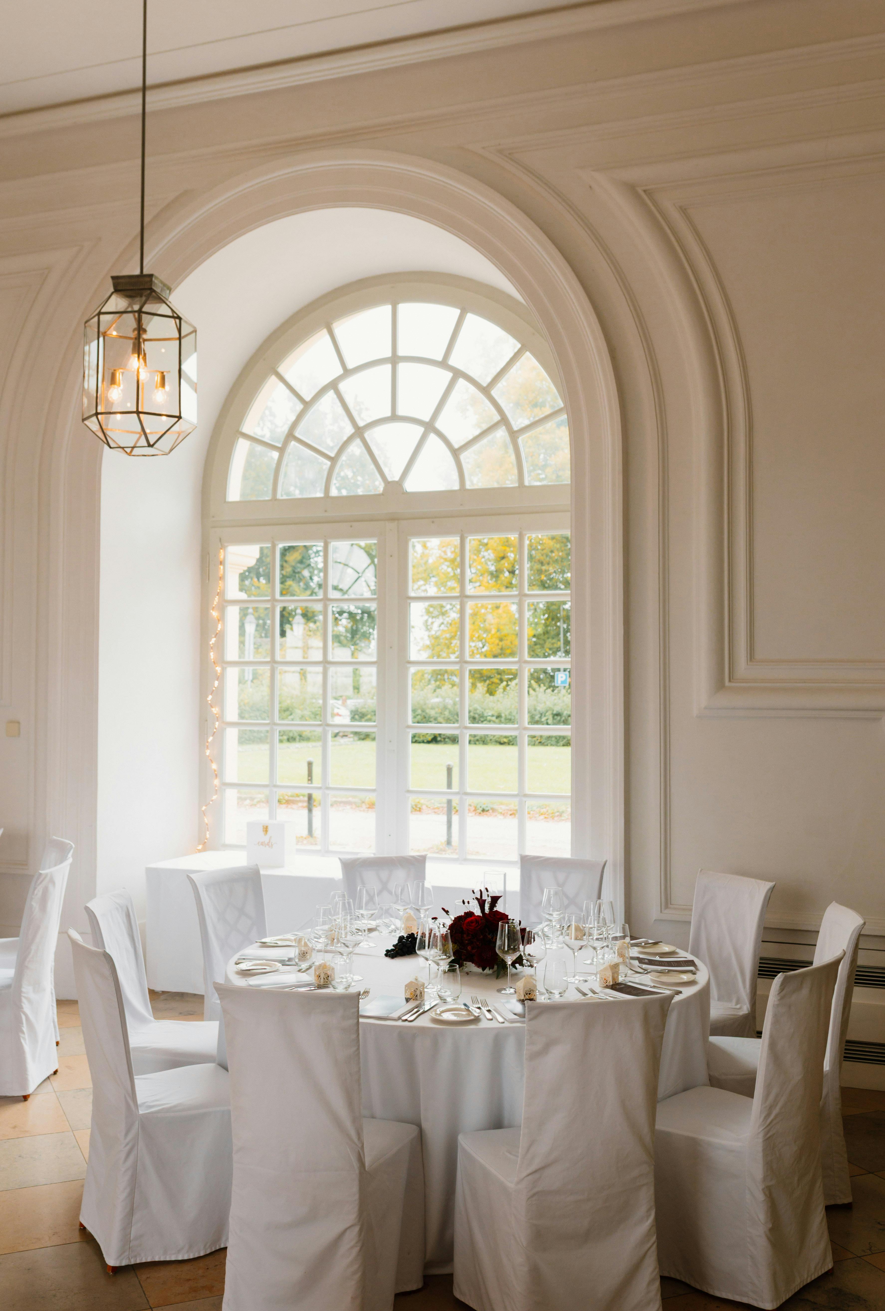 Chic wedding reception table in a bright, elegant room with natural light entering through large windows.