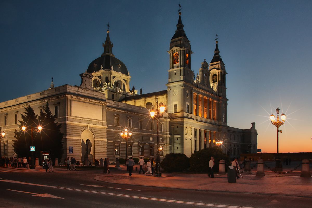 Catedrala Almudena iluminata la amurg, cu felinare si cer portocaliu