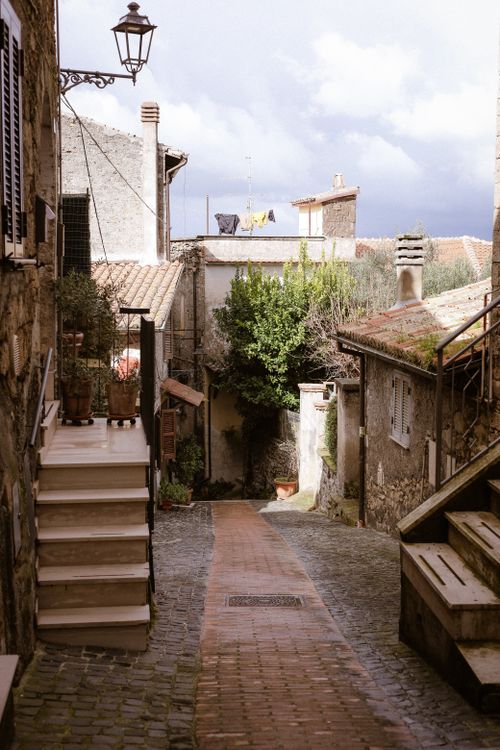 Free Picturesque Italian alley with rustic charm, bathed in sunlight, showcasing traditional architecture. Stock Photo