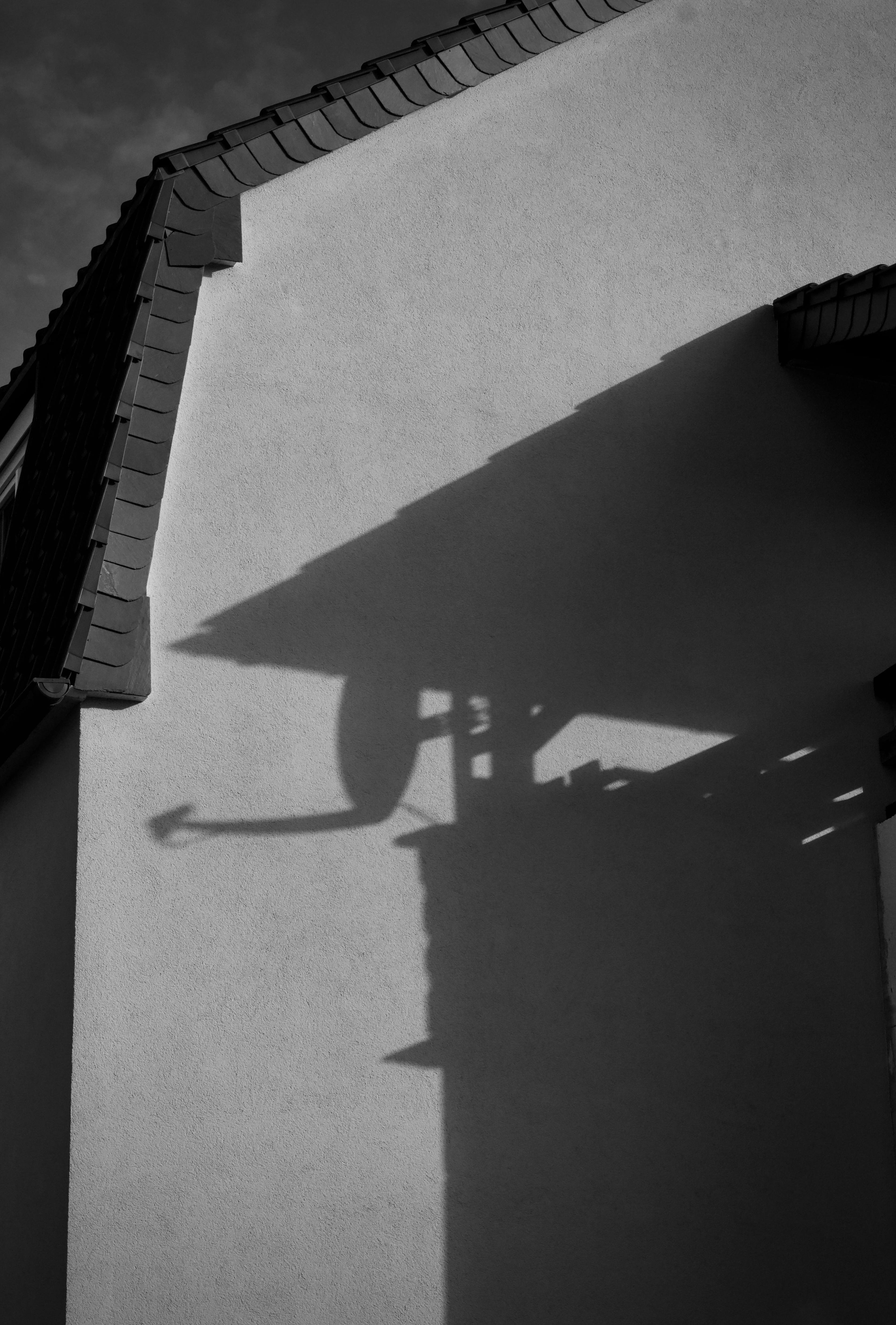 Kostenlos Schwarz-Weiß-Fotografie des Schattens einer Satellitenschüssel an einer Hauswand, wodurch eine abstrakte Stadtszene entsteht. Stock-Foto