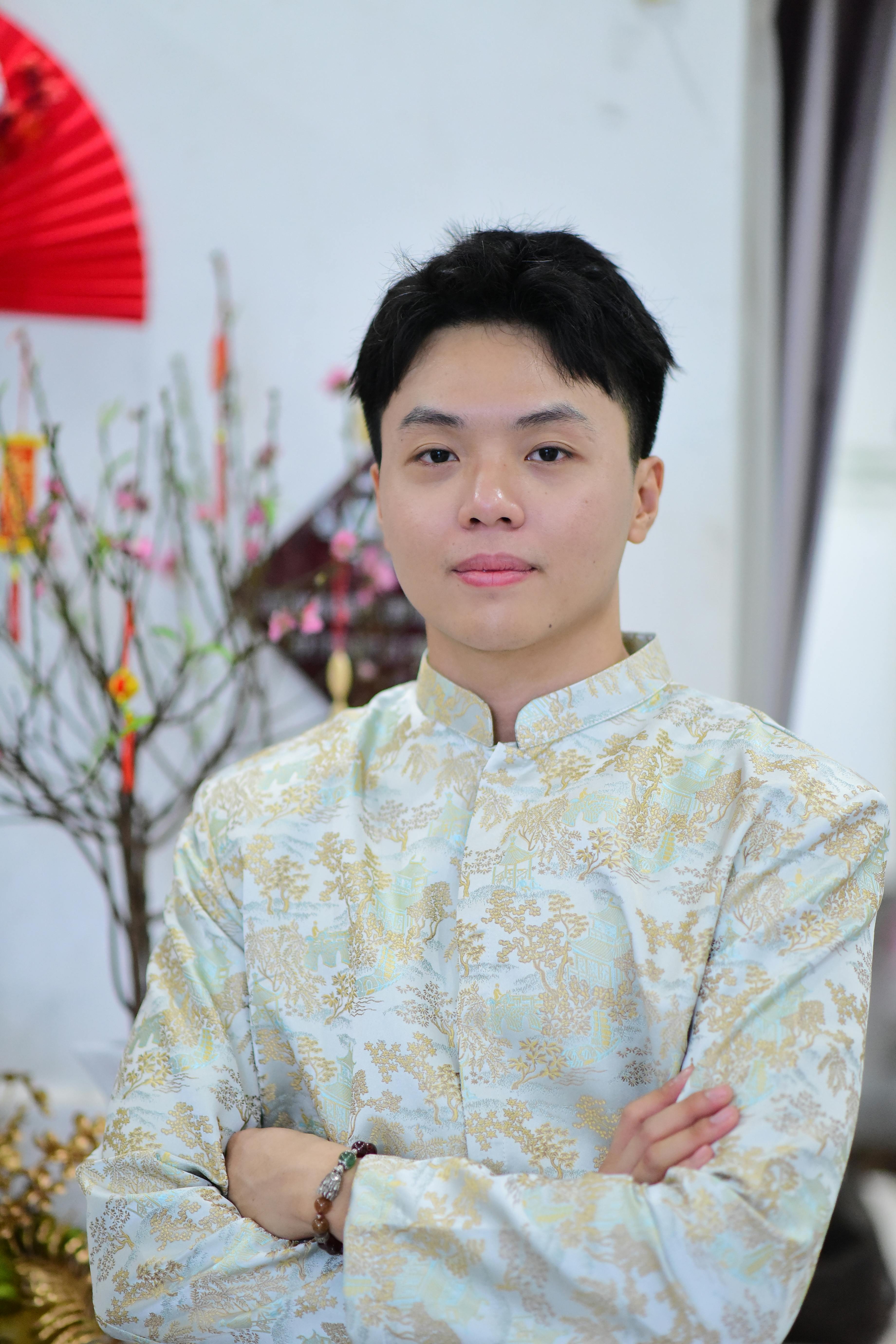 Portrait of a male in traditional Asian attire indoors, celebrating an occasion.