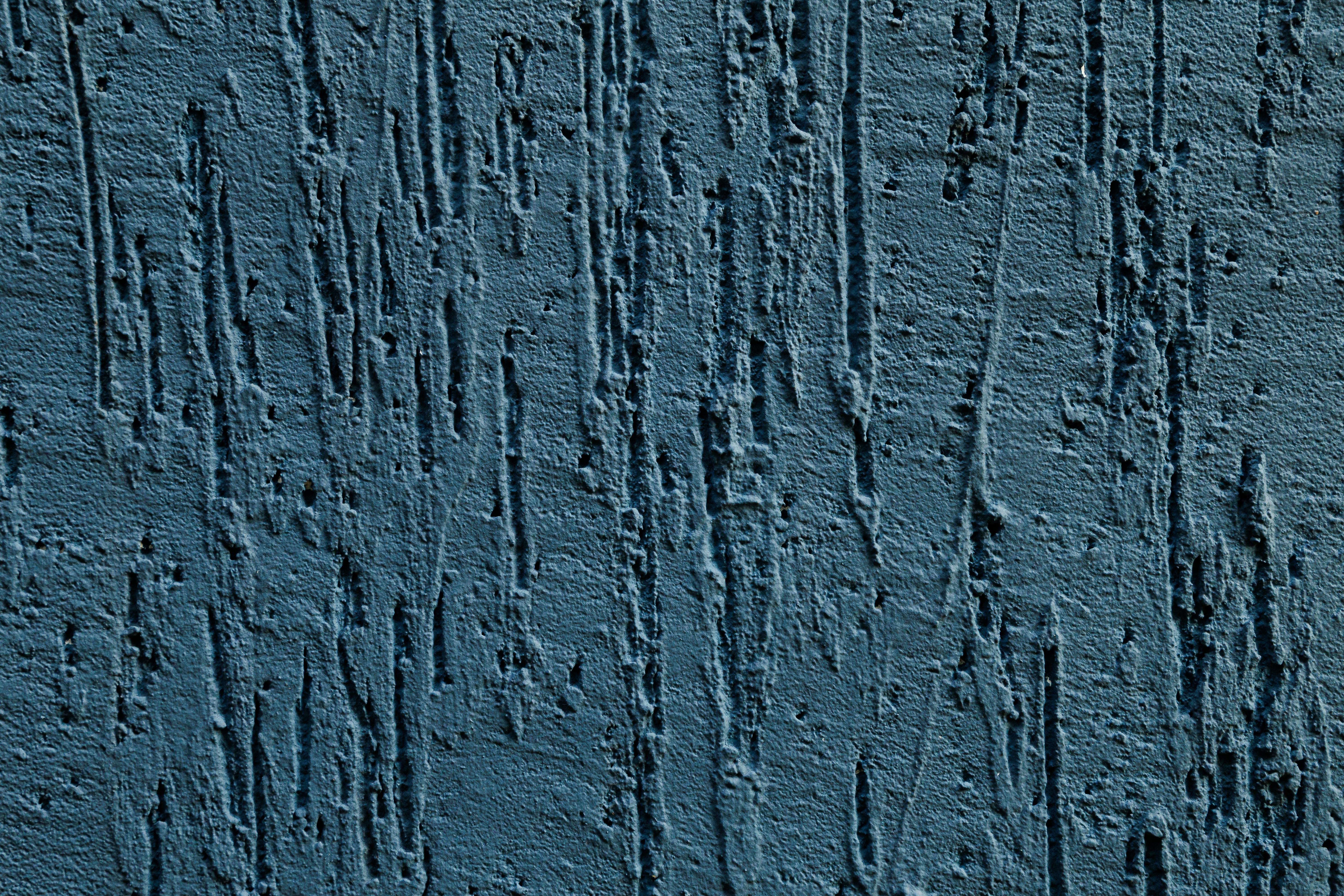 бесплатная Крупный план синей текстурированной бетонной поверхности, демонстрирующий грубые вертикальные линии и уникальные узоры. Стоковое фото