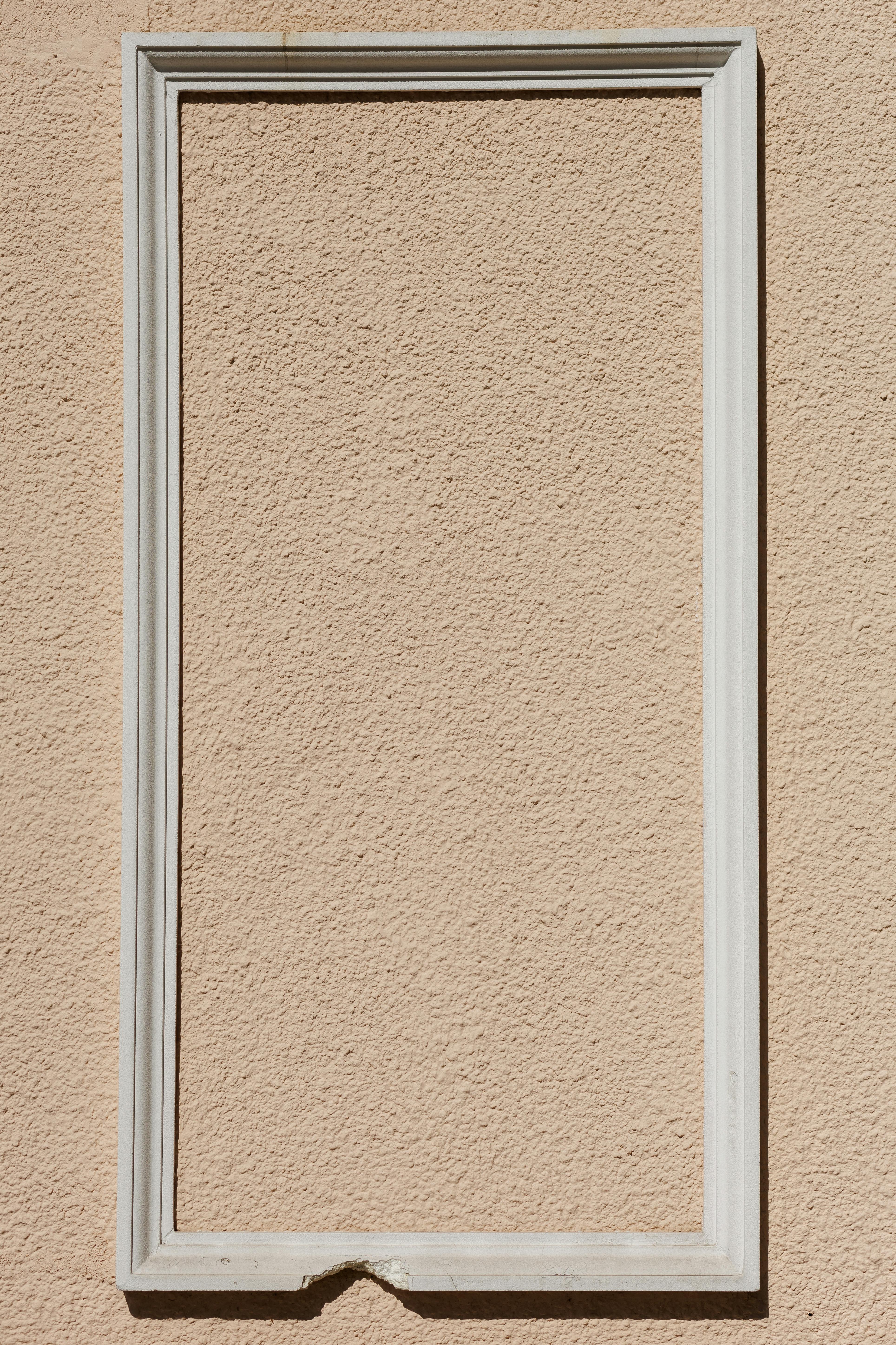 Gratis Una cornice bianca su una parete beige testurizzata illuminata dalla luce naturale, design minimalista. Foto a disposizione