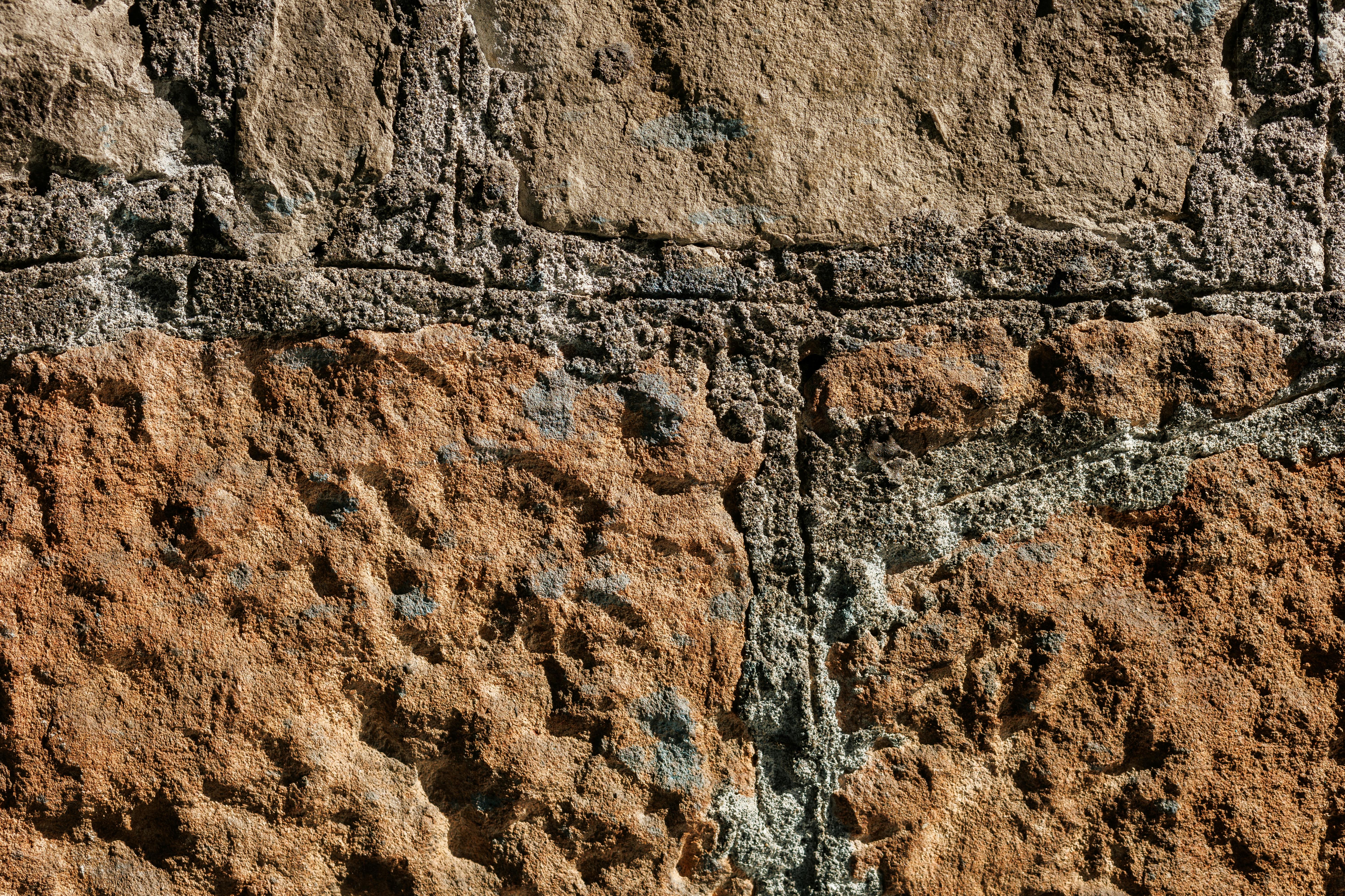 Free Detailed close-up of a weathered stone wall showcasing texture and natural weathering patterns. Stock Photo