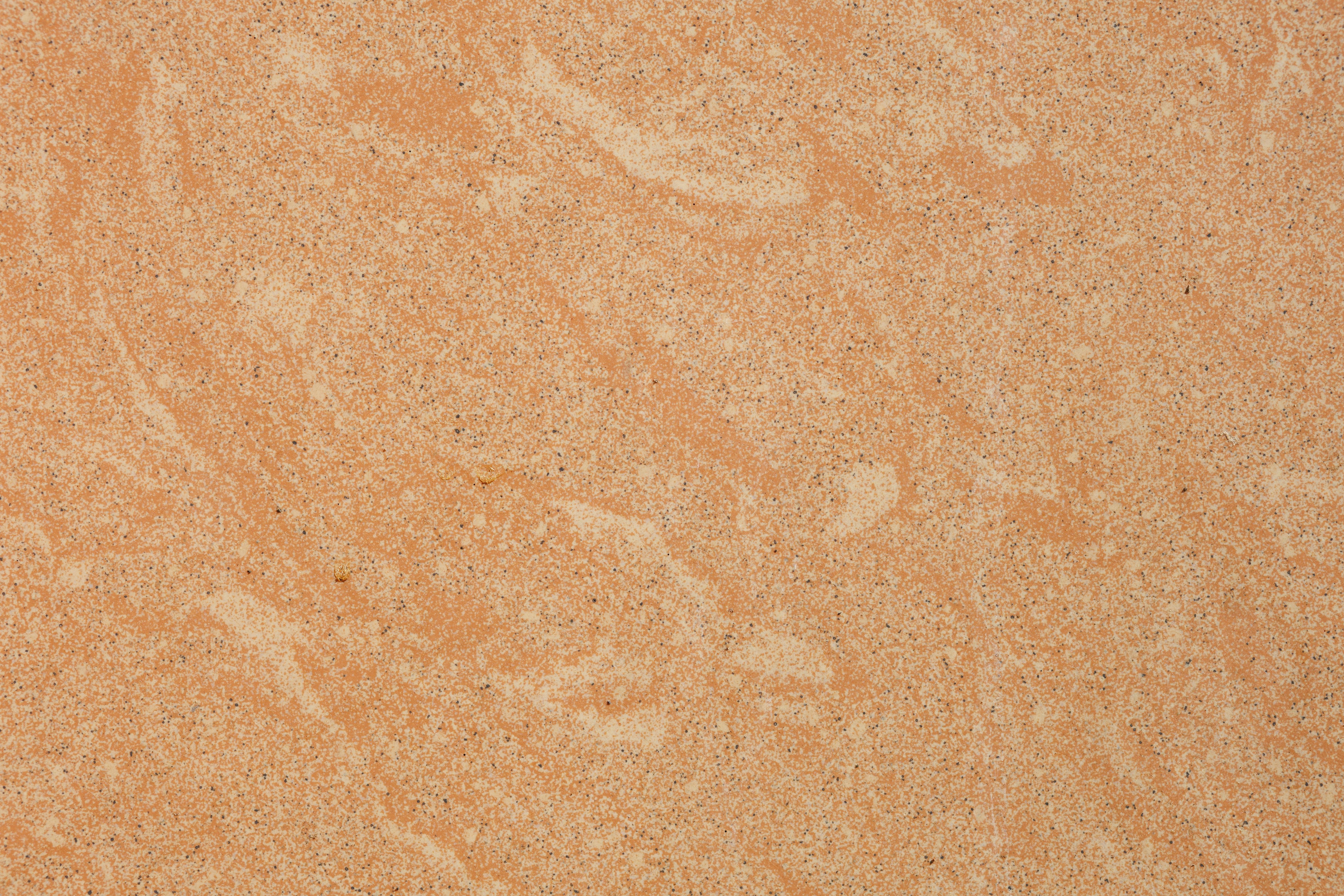 Free Close-up of a natural stone surface featuring a warm orange texture with subtle patterns. Stock Photo