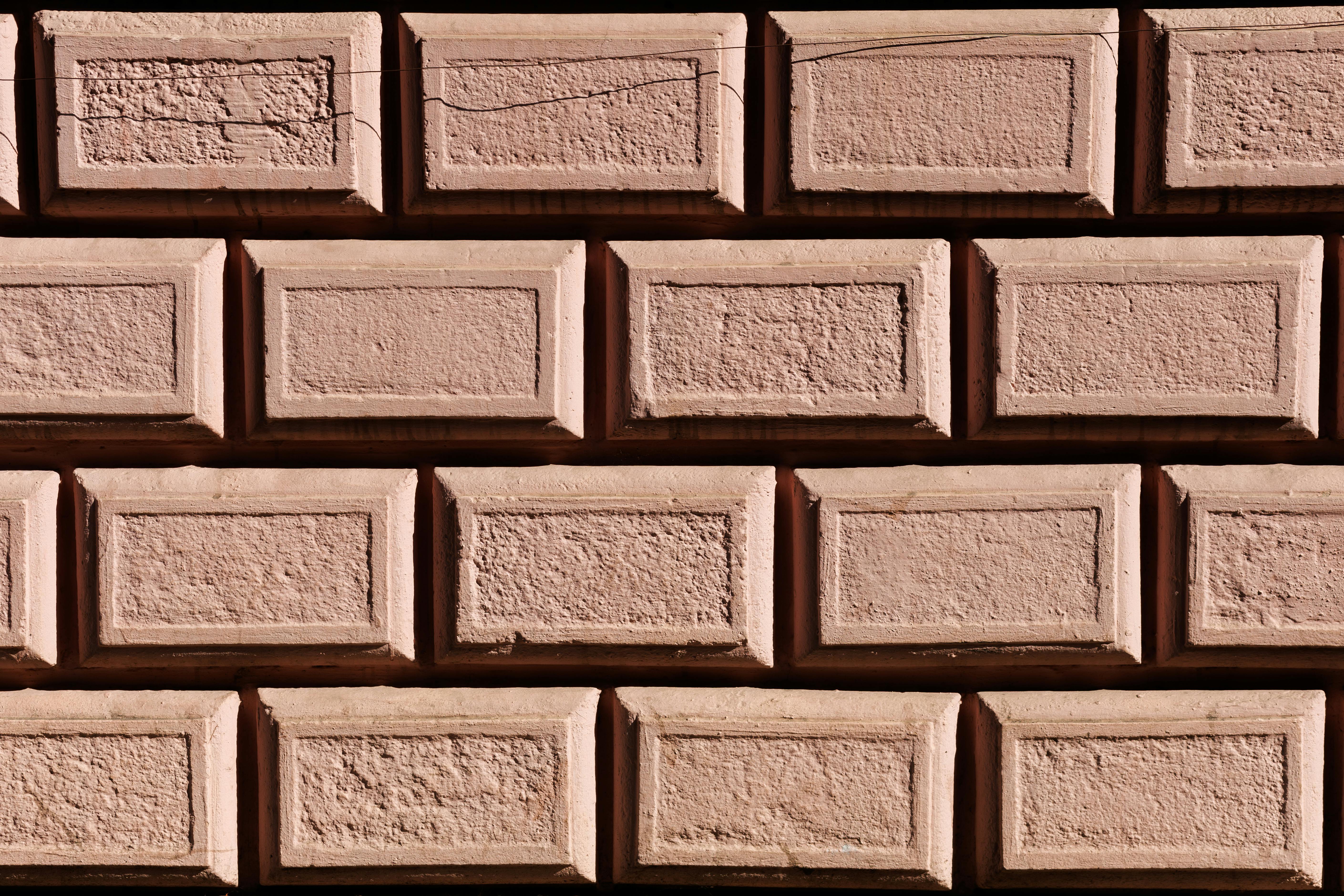 Δωρεάν Κοντινή άποψη ενός τοίχου από ροζ τούβλα με υφή που παρουσιάζει γεωμετρικά μοτίβα και σκιές. Φωτογραφία από στοκ φωτογραφιών