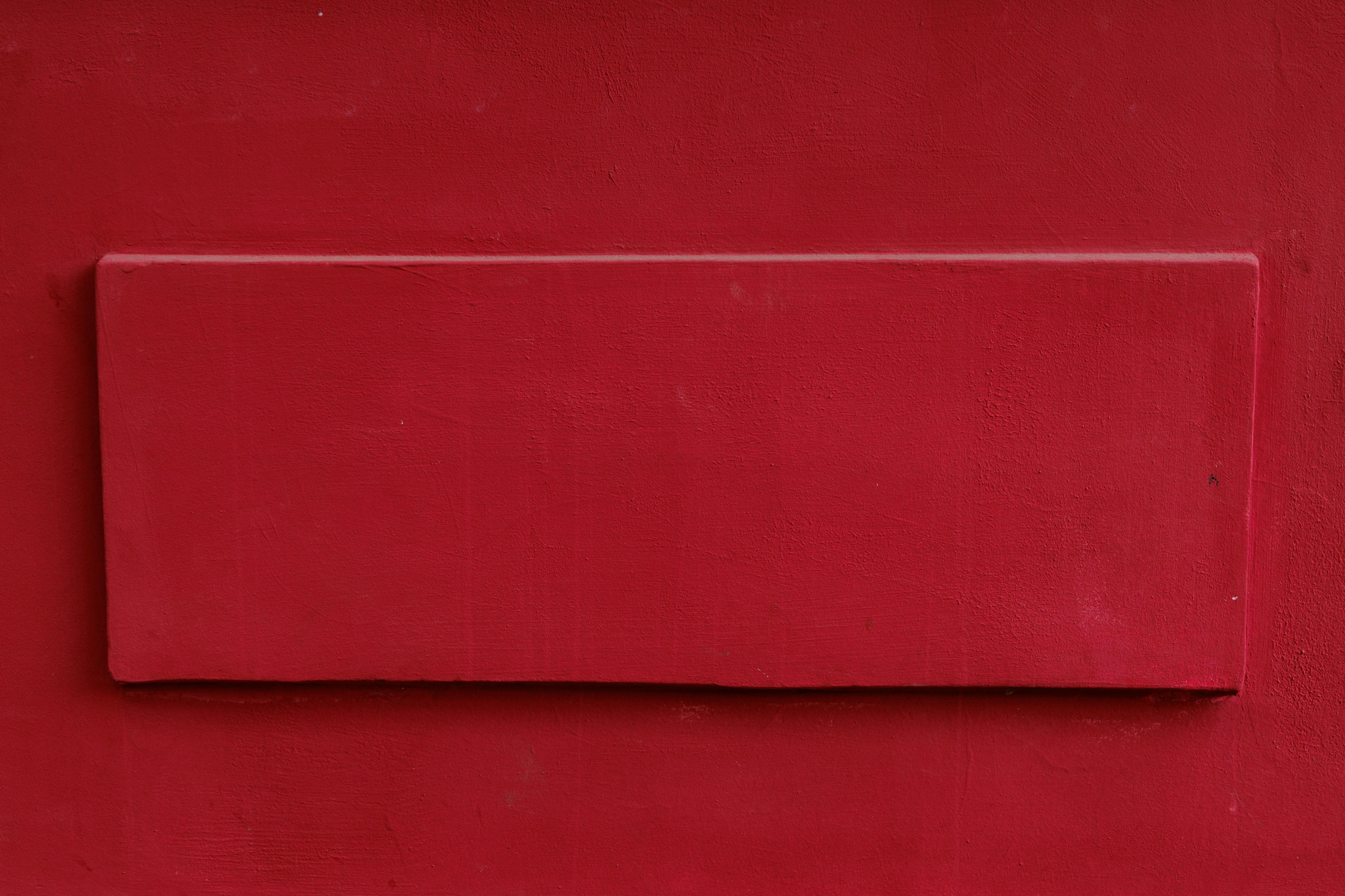 De franc Una paret vermella minimalista amb una secció rectangular elevada, que crea un contrast atrevit. Foto d'estoc