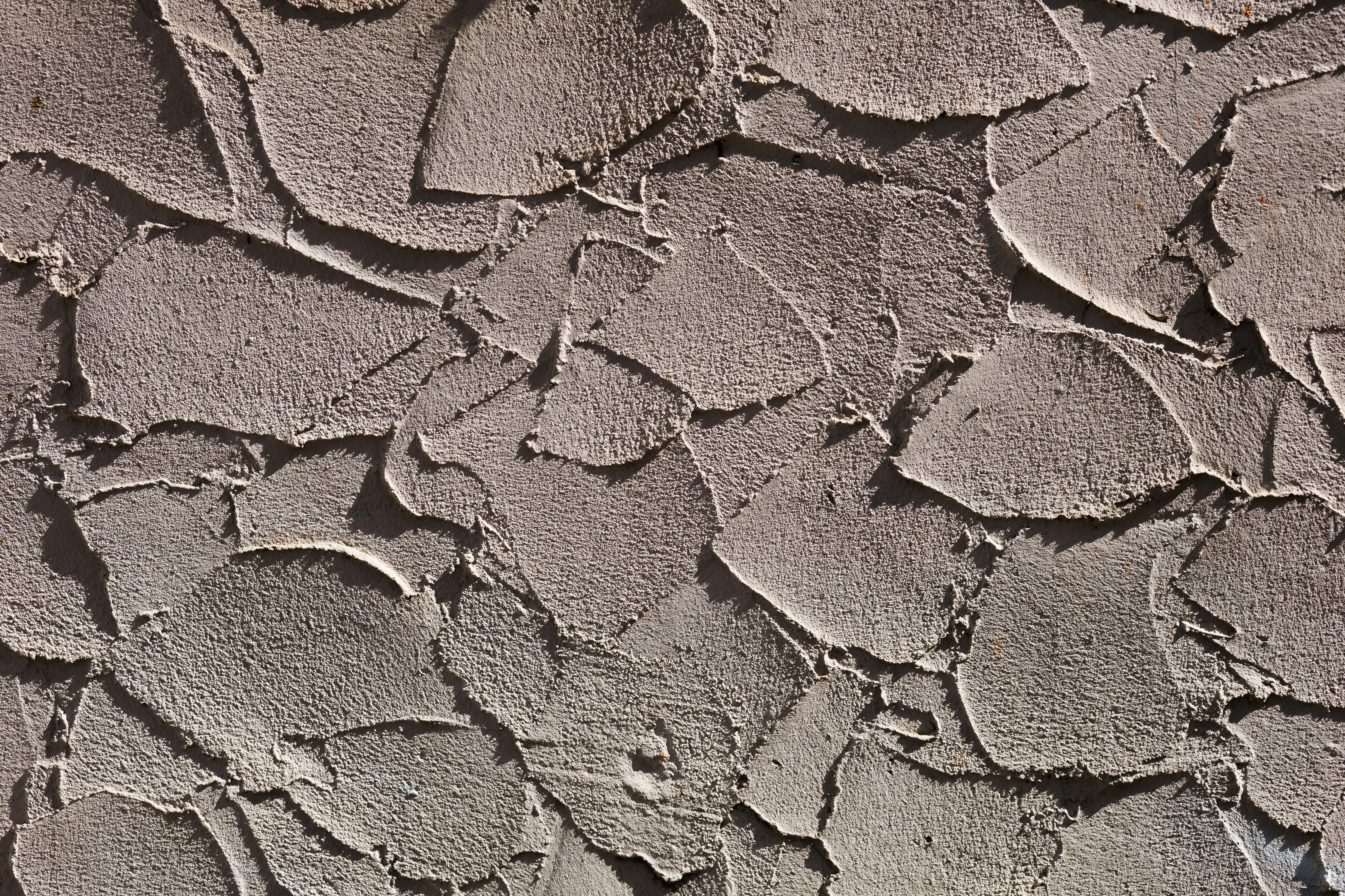 бесплатная Детальный крупный план грубой фактурной стены, демонстрирующий слои штукатурки. Стоковое фото