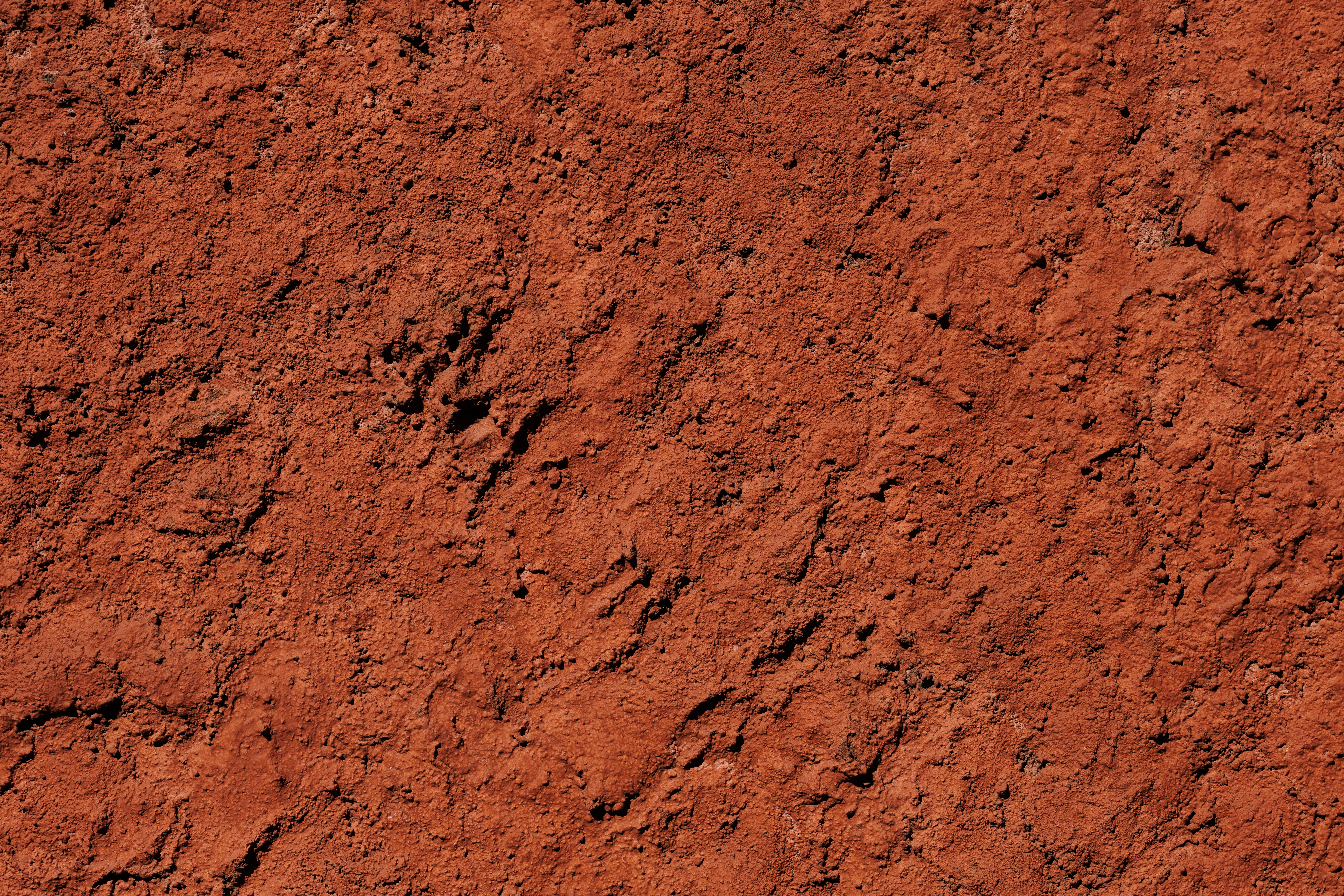 Close-up texture of dense red-orange clay soil — nearly impermeable and the primary cause of poor yard drainage in Indianapolis and Chicago