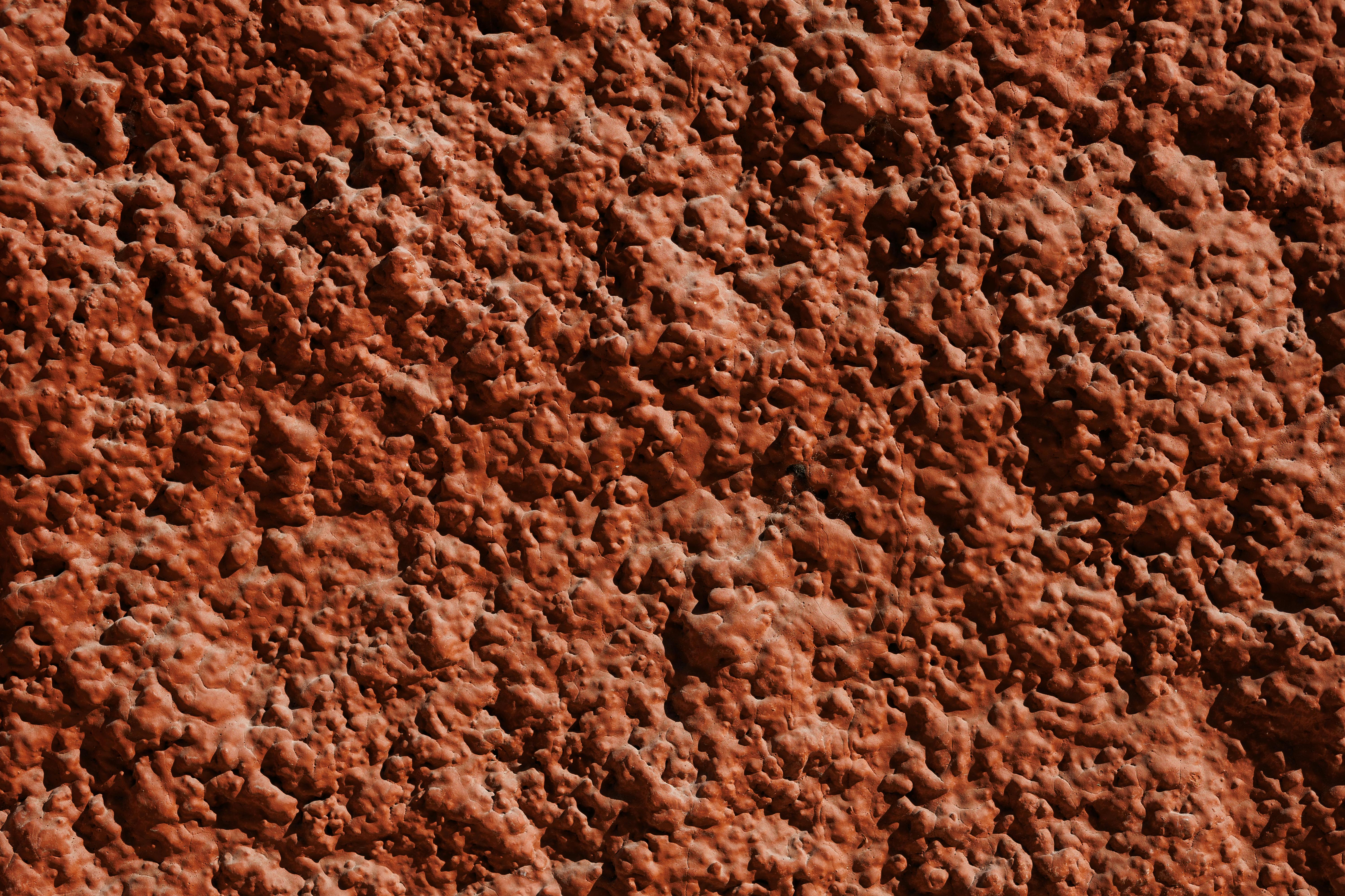 Gratis Nærbillede af en rød, stenet overfladetekstur med indviklede detaljer og et robust mønster. Lagerfoto