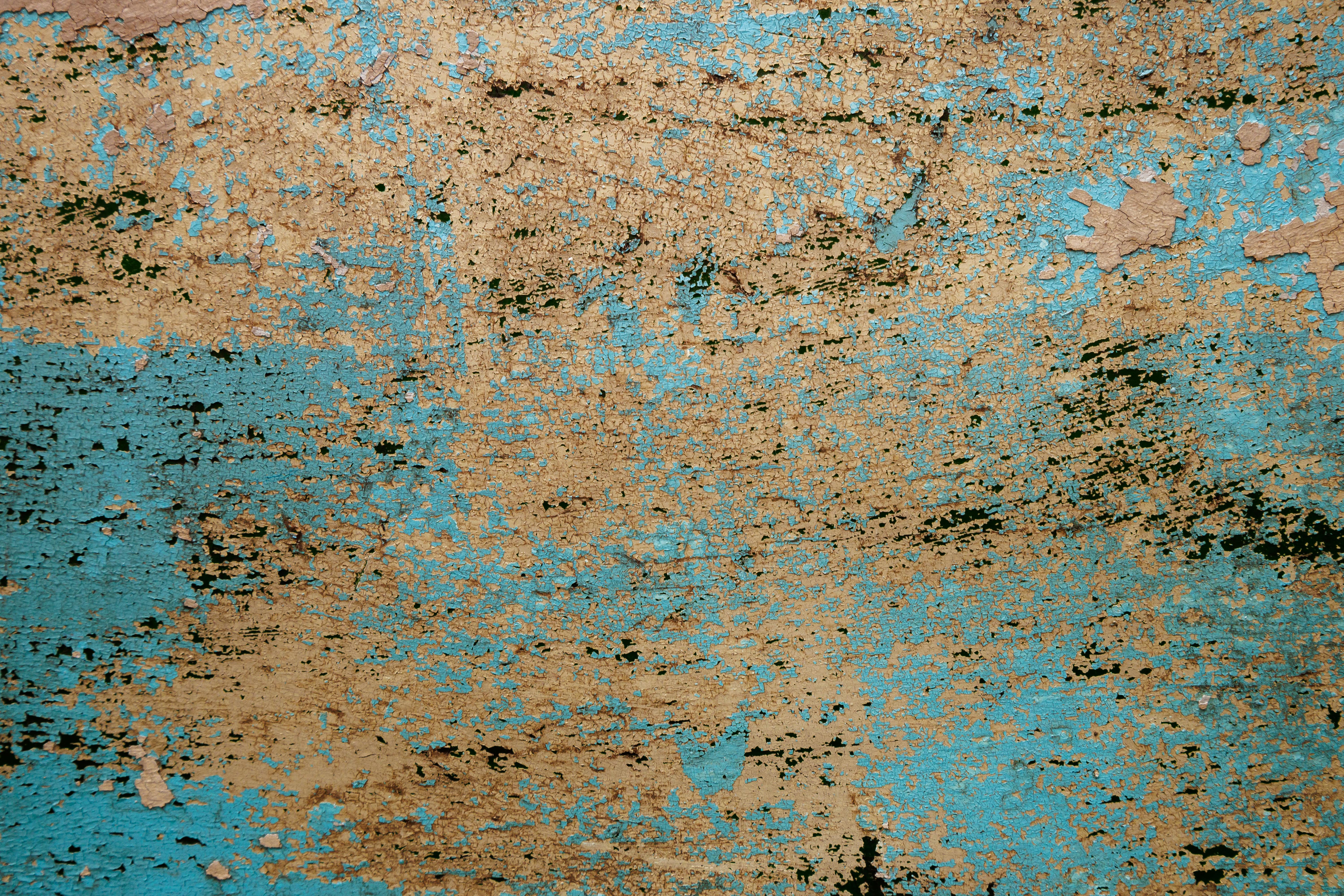 grátis Detalhe de uma parede com tinta descascando em tons de azul e bege, criando uma textura abstrata. Foto profissional