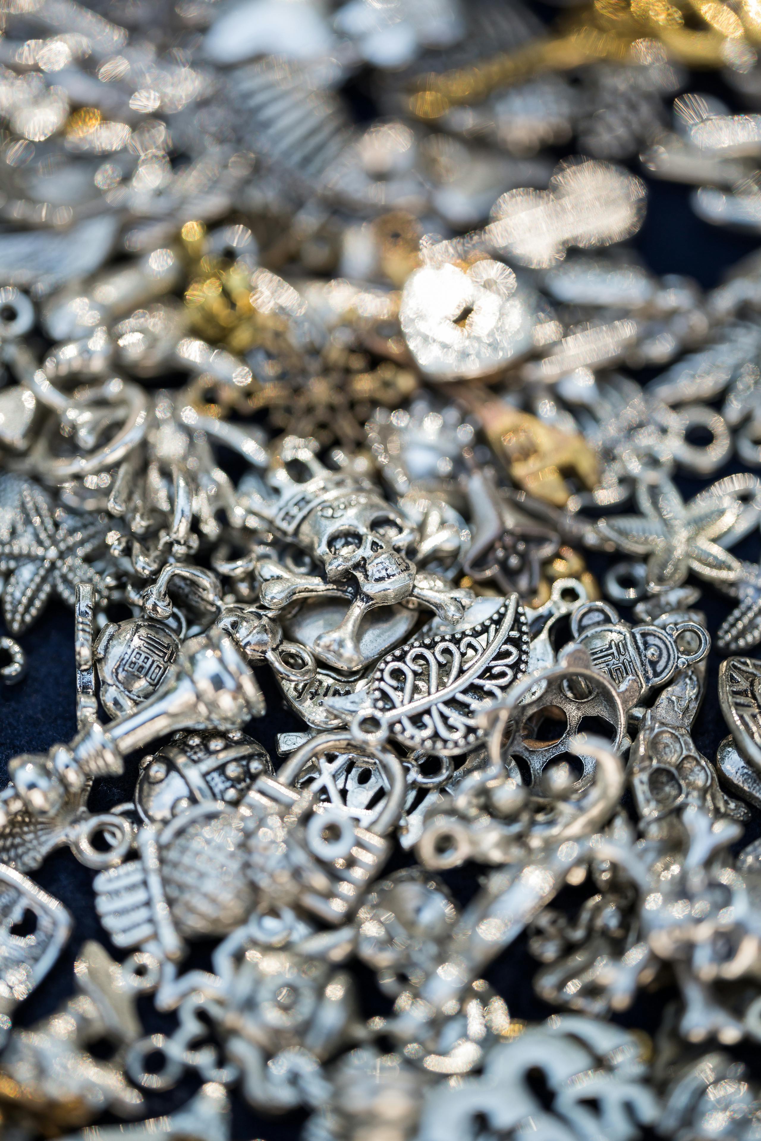 Kostenlos Eine Nahaufnahme verschiedener Silberanhänger mit aufwendigen Designs und Texturen, perfekt für die Schmuckherstellung oder Bastelarbeiten. Stock-Foto