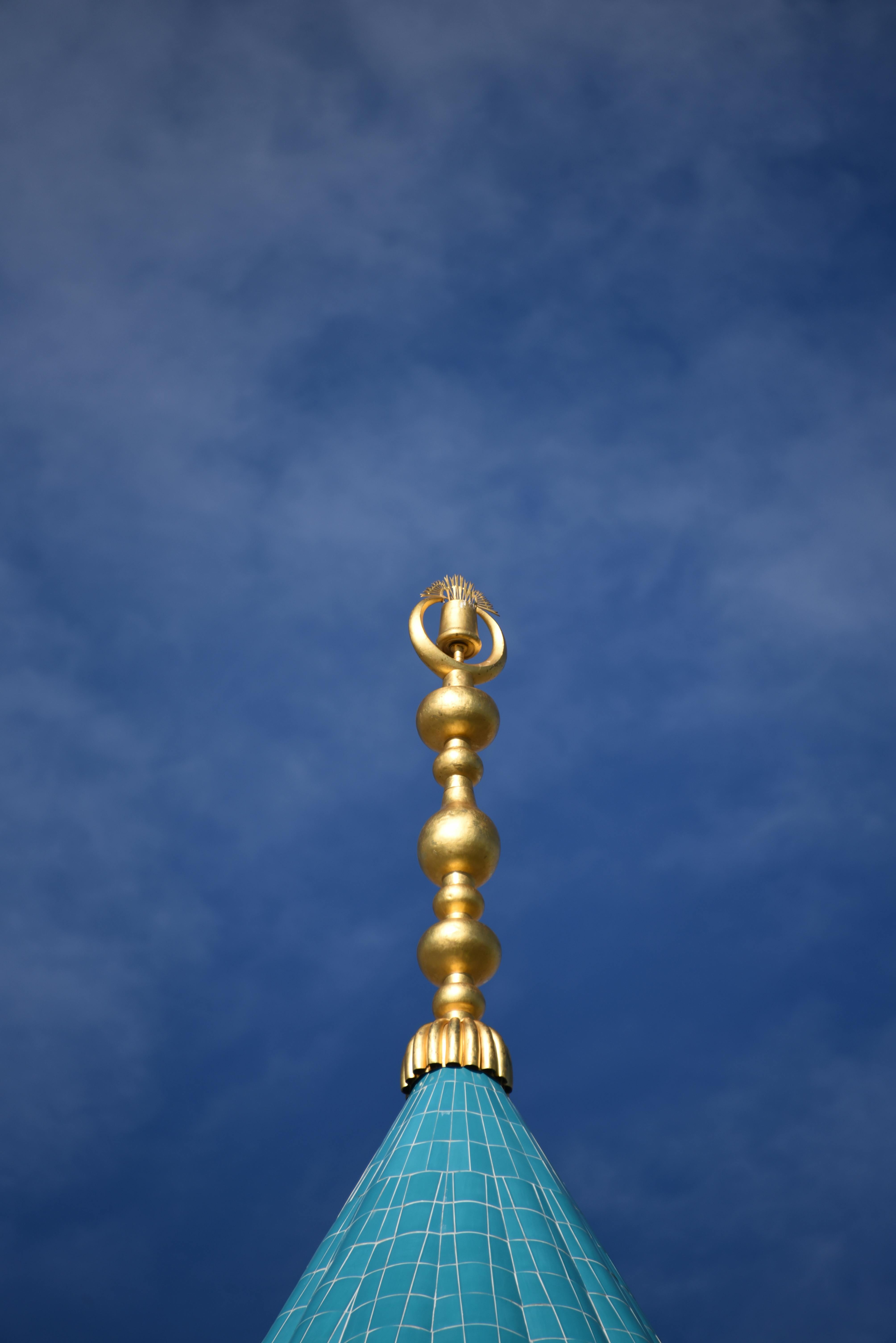 Kostenlos Eine goldene Turmspitze erhebt sich vor einem klaren blauen Himmel und bietet ein friedvolles architektonisches Detail. Stock-Foto