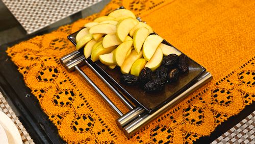 Free Sliced apples and prunes on a sleek black platter over a vibrant orange lace tablecloth. Stock Photo