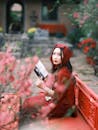 Woman in Red Reading Amidst Blossoms