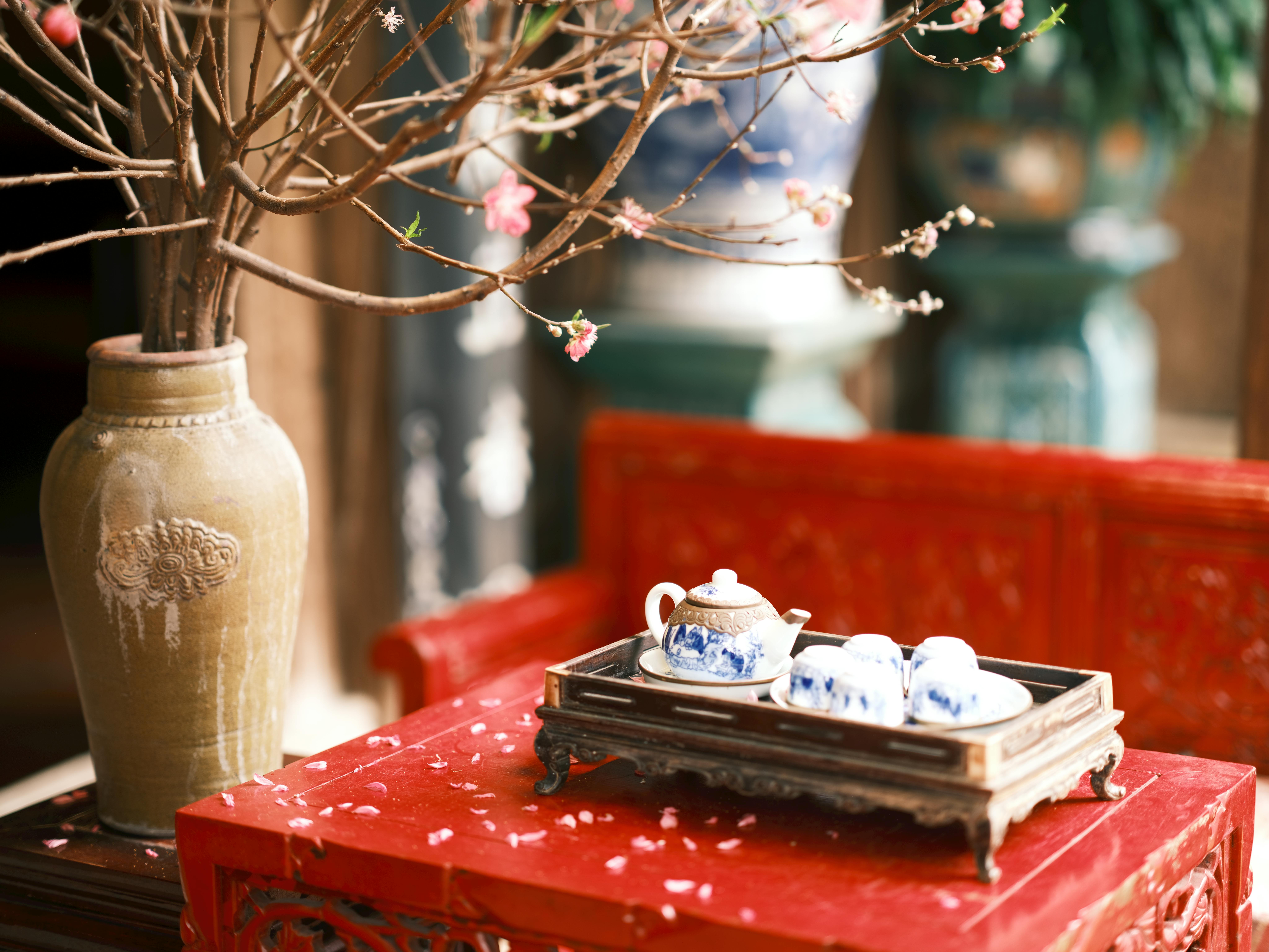бесплатная Традиционный китайский чайный сервиз с декоративной вазой на красном столе, украшенный цветущими ветвями. Стоковое фото