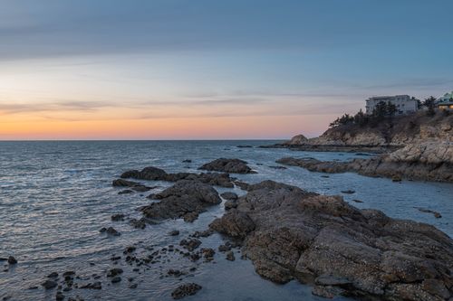 Free Beautiful sunset view over a rocky coastline, with serene ocean waves and a clear sky. Stock Photo