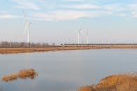 Wind turbines near a serene lakeside view