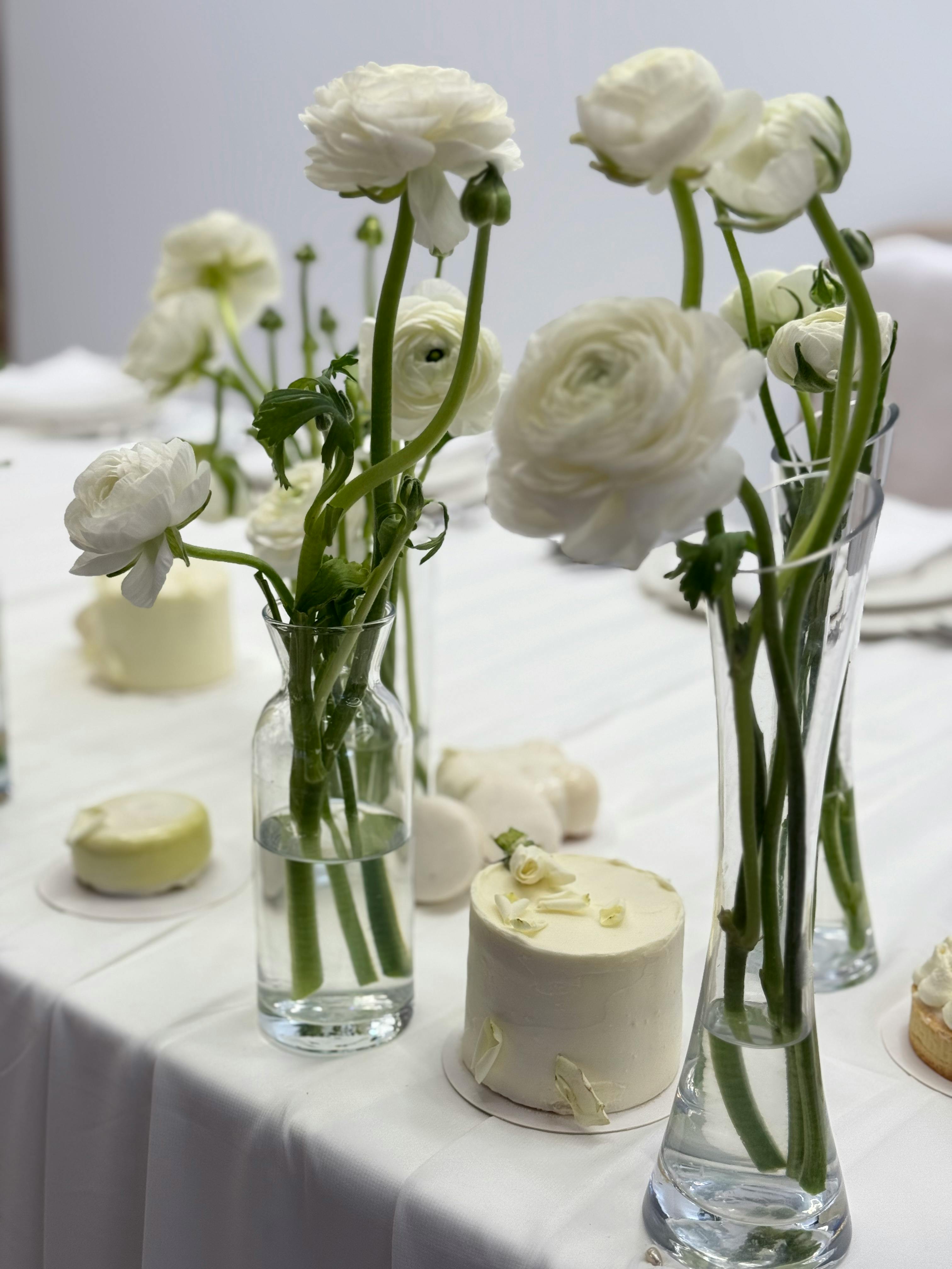 Kostenlos Eine elegante Tischdekoration mit weißen Blumen und Kuchen, ideal für Hochzeiten oder Feierlichkeiten. Stock-Foto