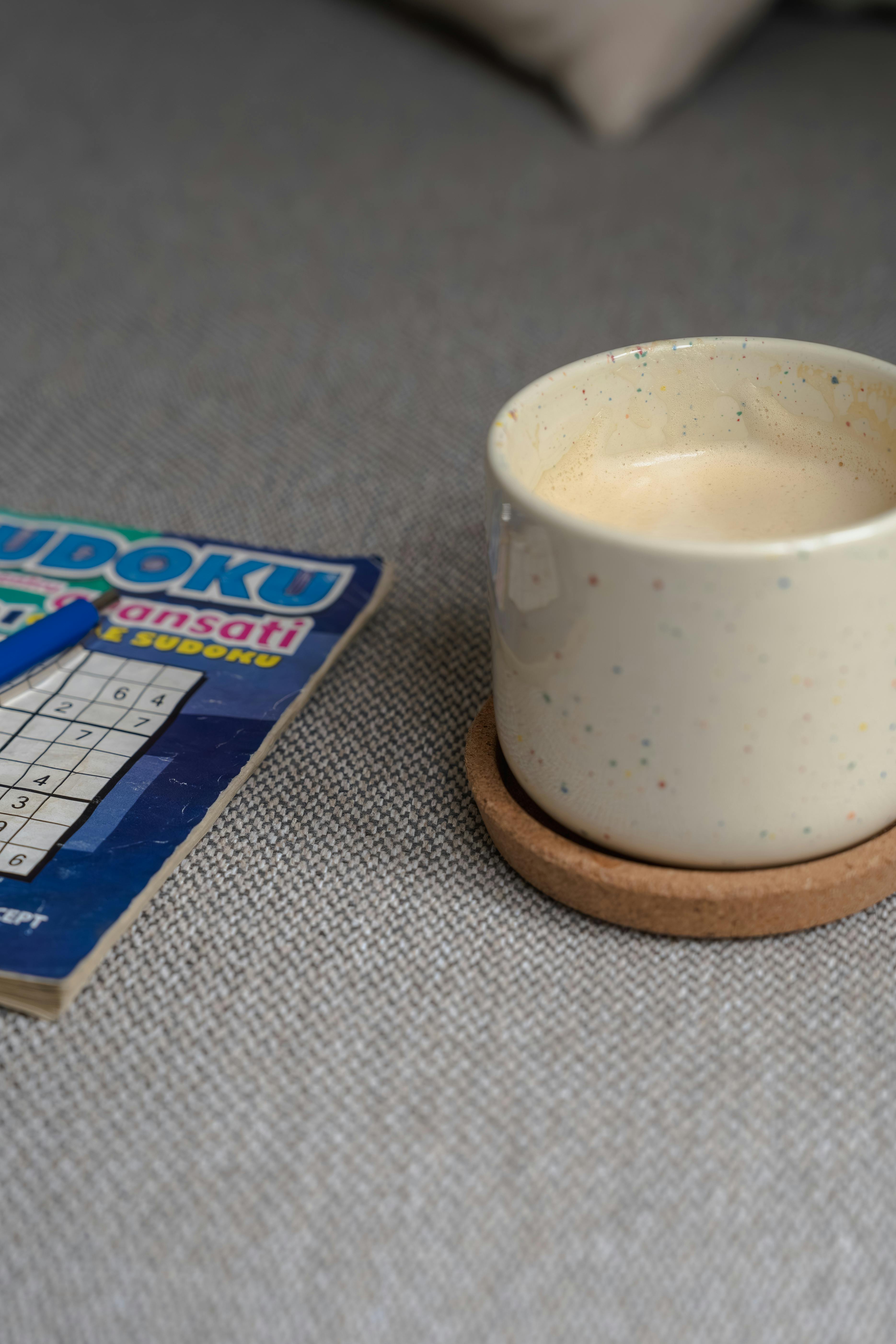 Δωρεάν Μια χαλαρωτική σκηνή με μια κούπα καφέ και ένα βιβλίο Sudoku, ιδανική για χαλάρωση και δραστηριότητες αναψυχής. Φωτογραφία από στοκ φωτογραφιών