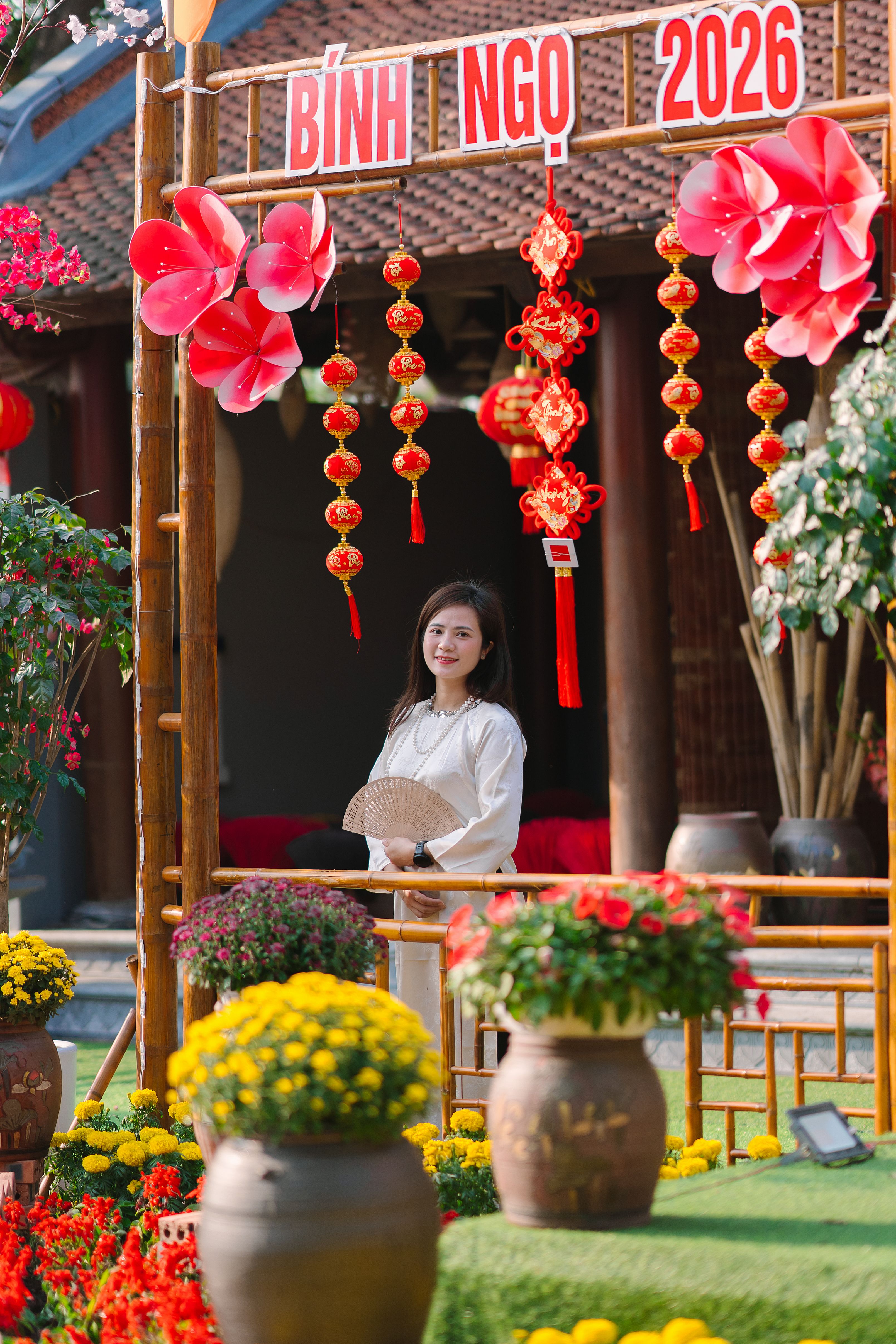 Young woman in traditional setting celebrating the Vietnamese New Year with flowers and decorations.