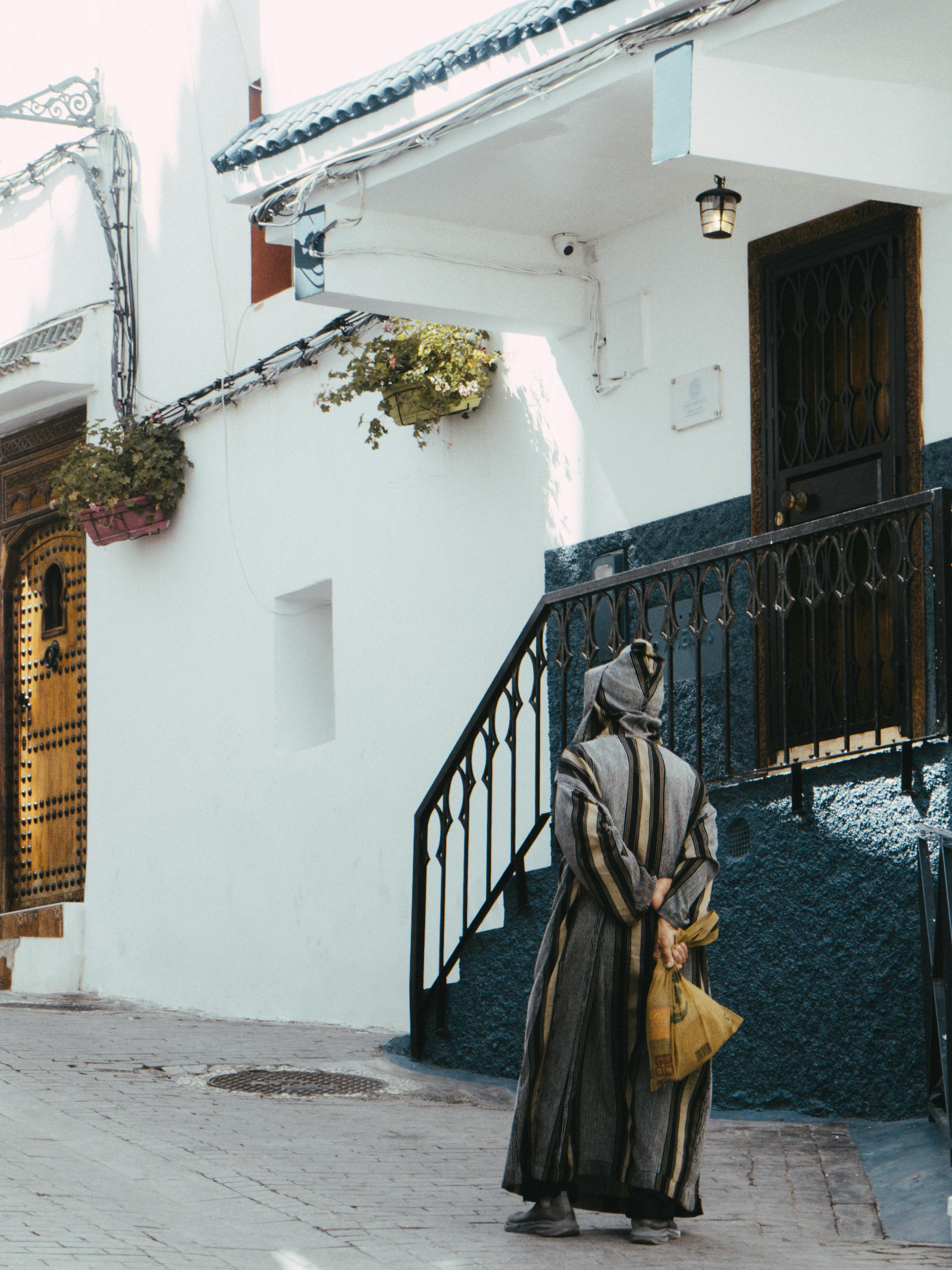 Gratis En kvinne i tradisjonelle klær går gjennom en livlig gate i Tanger i Marokko. Arkivbilde