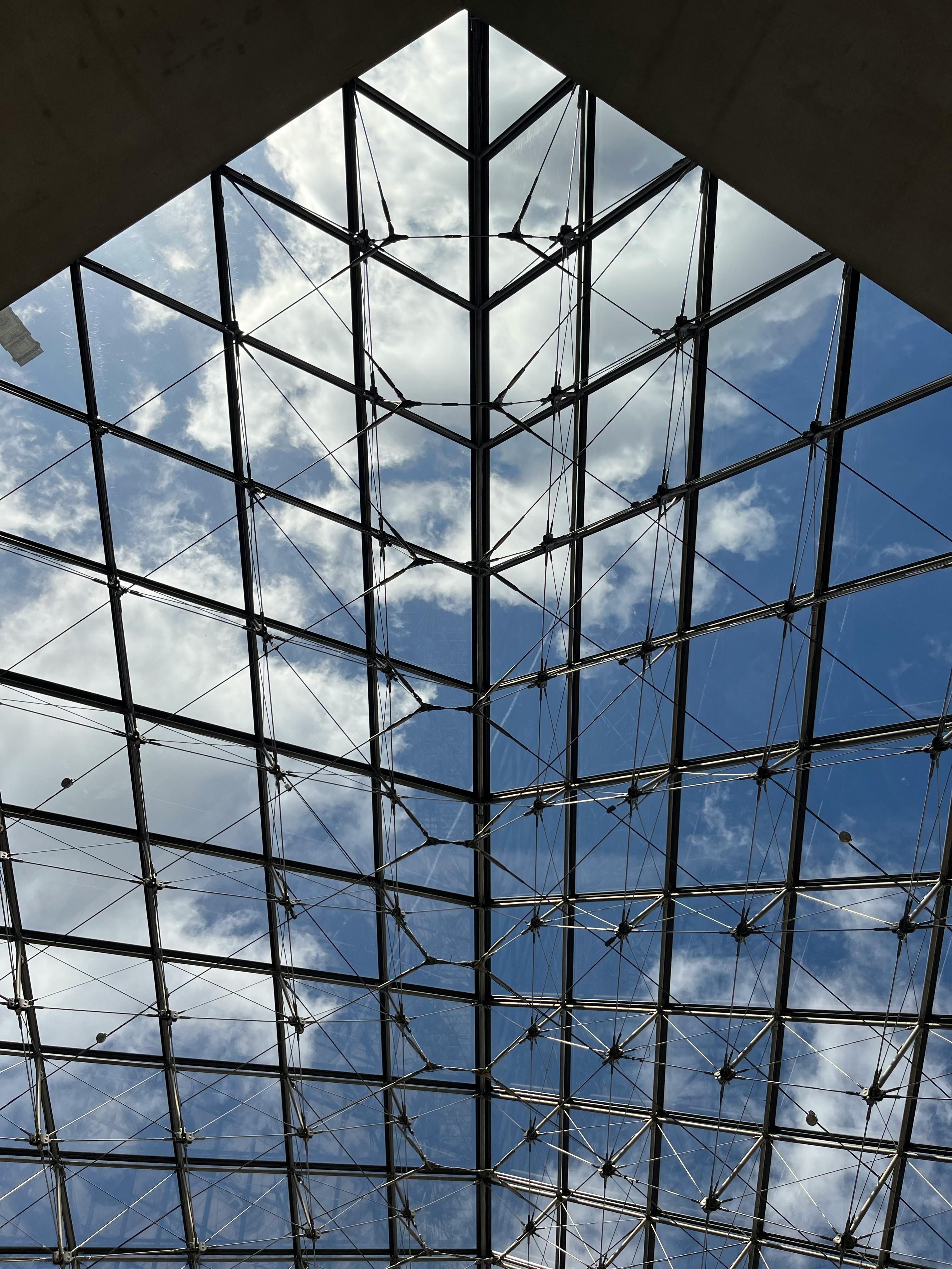 Gratis Utsikt over glasspyramidetaket mot en blå himmel på Louvre-museet i Paris. Arkivbilde